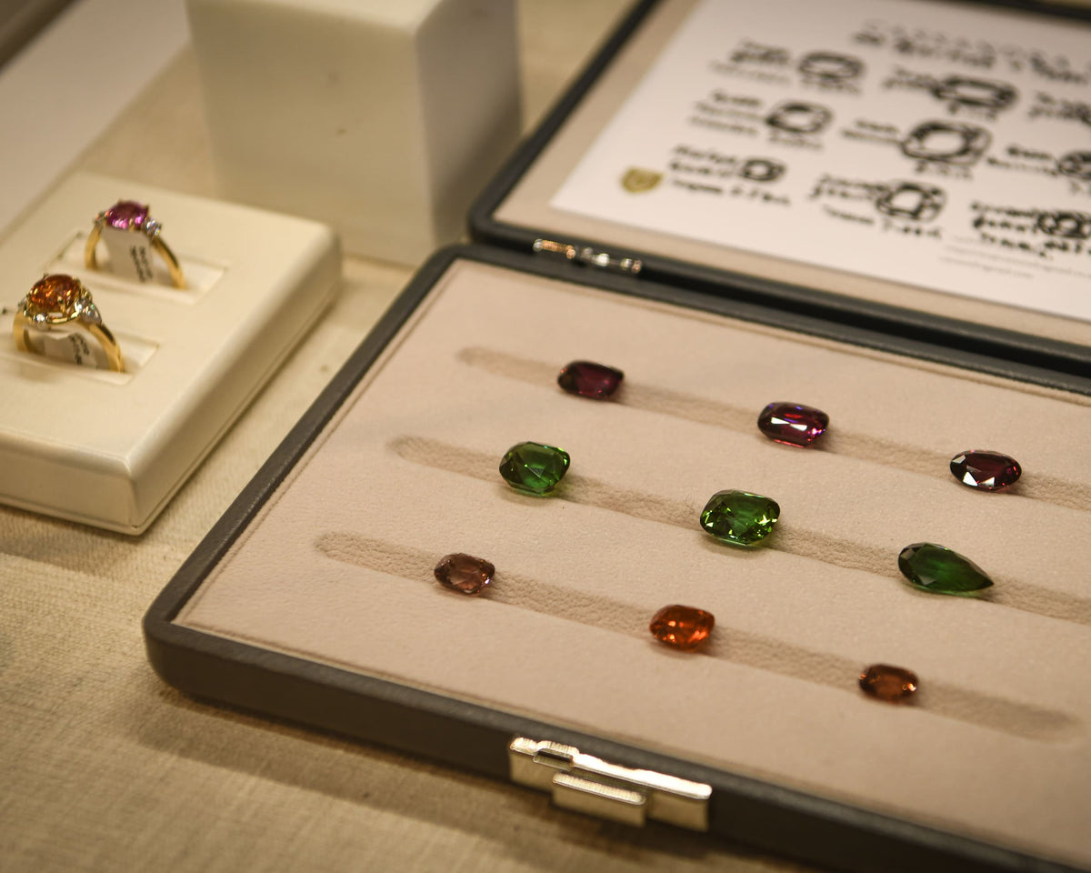 Gemstones of different colours and cuts with two engagement rings on the left