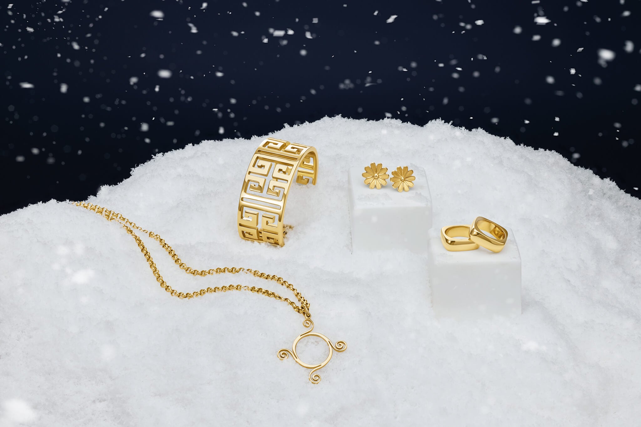 Gold jewelry including a bracelet, necklace, and earrings on a snowy background