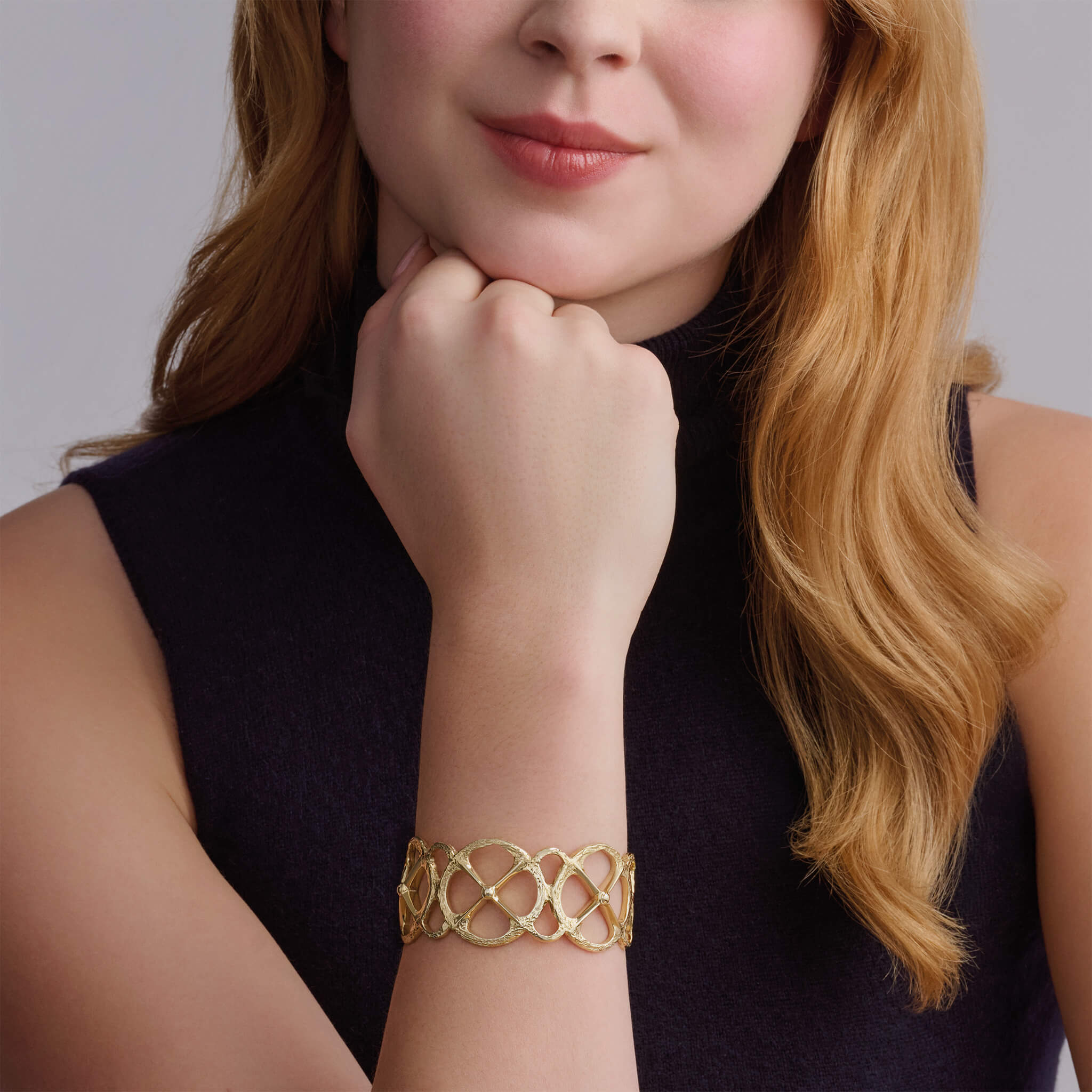 Model wearing handcrafted precious metal cuff bracelet with a circular motif and a cross in the middle.