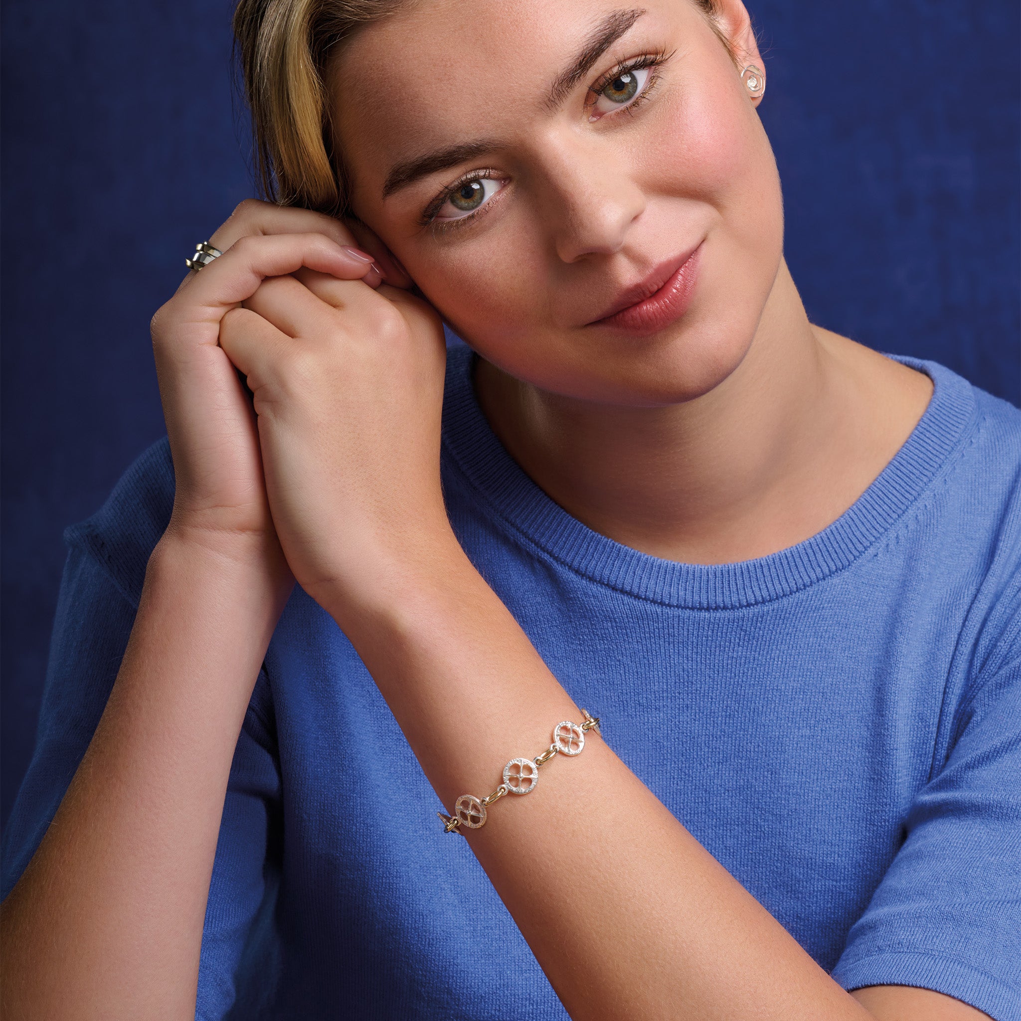 Model wearing handcrafted sterling silver and yellow gold bracelet with a circular motif and a cross in the middle.