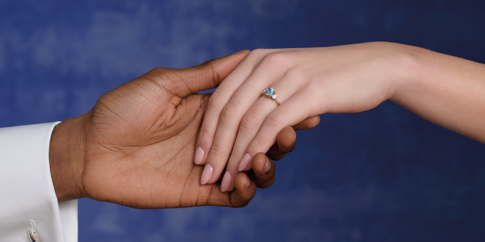 Couple holding hands, wearing Cassandra Goad blue gemstone engagement ring