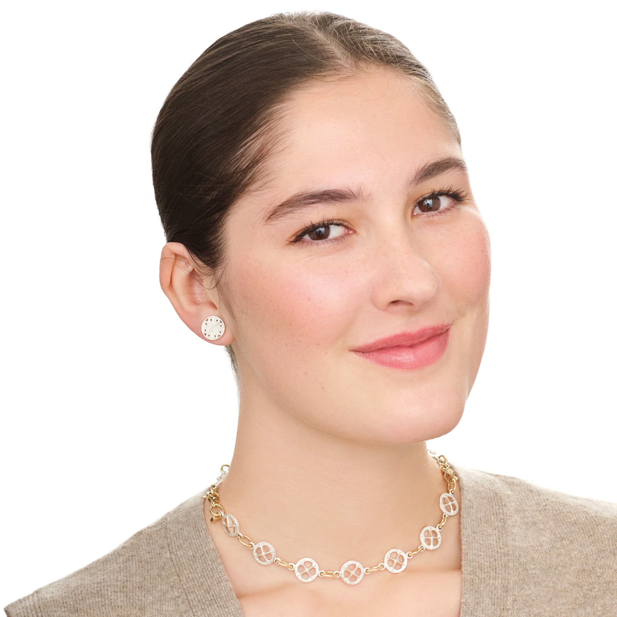 Model wears handcrafted silver circular earring studs with a cross-like motif in the centre.