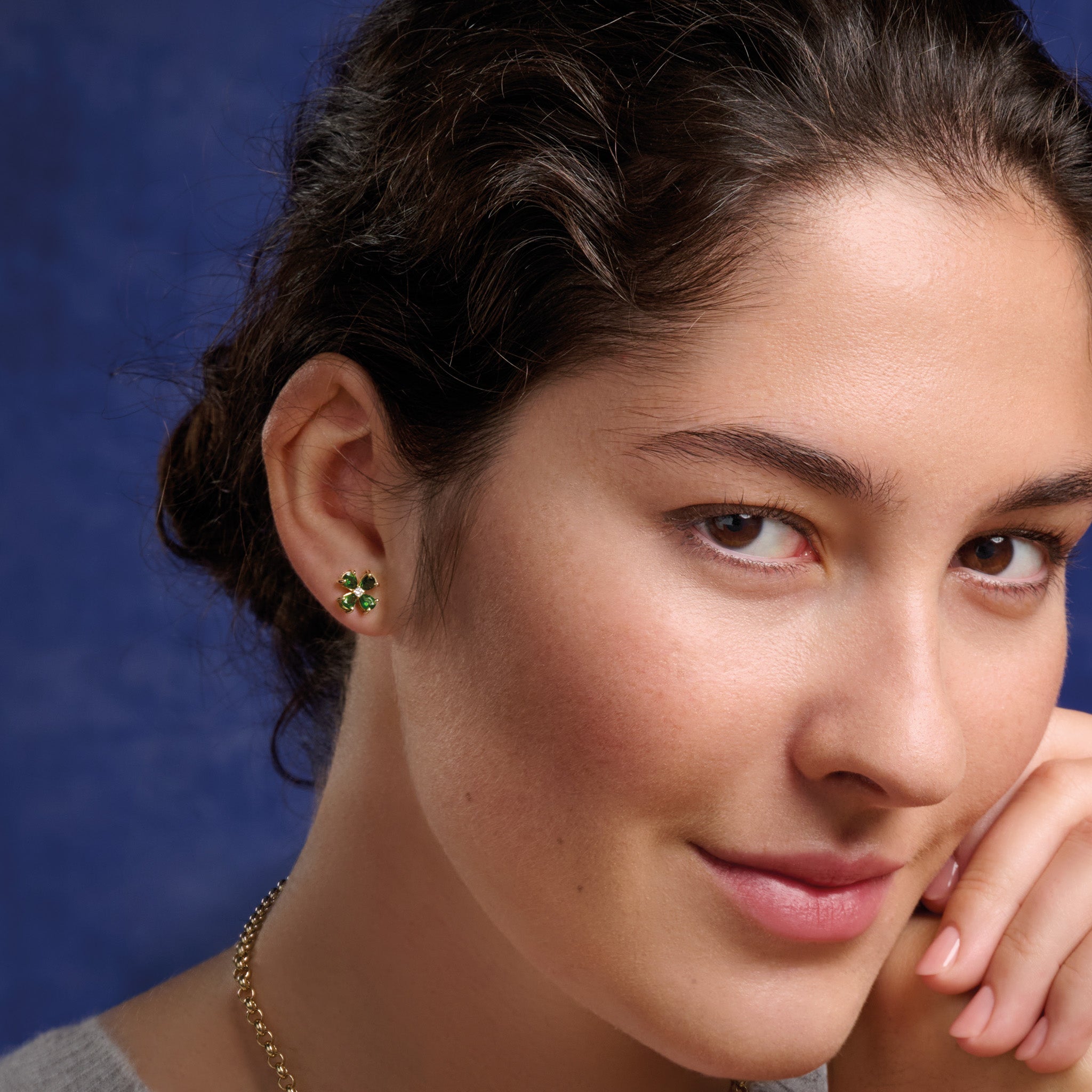 Model wearing handcrafted 9ct yellow gold four-leaf clover stud earrings with precious stones.