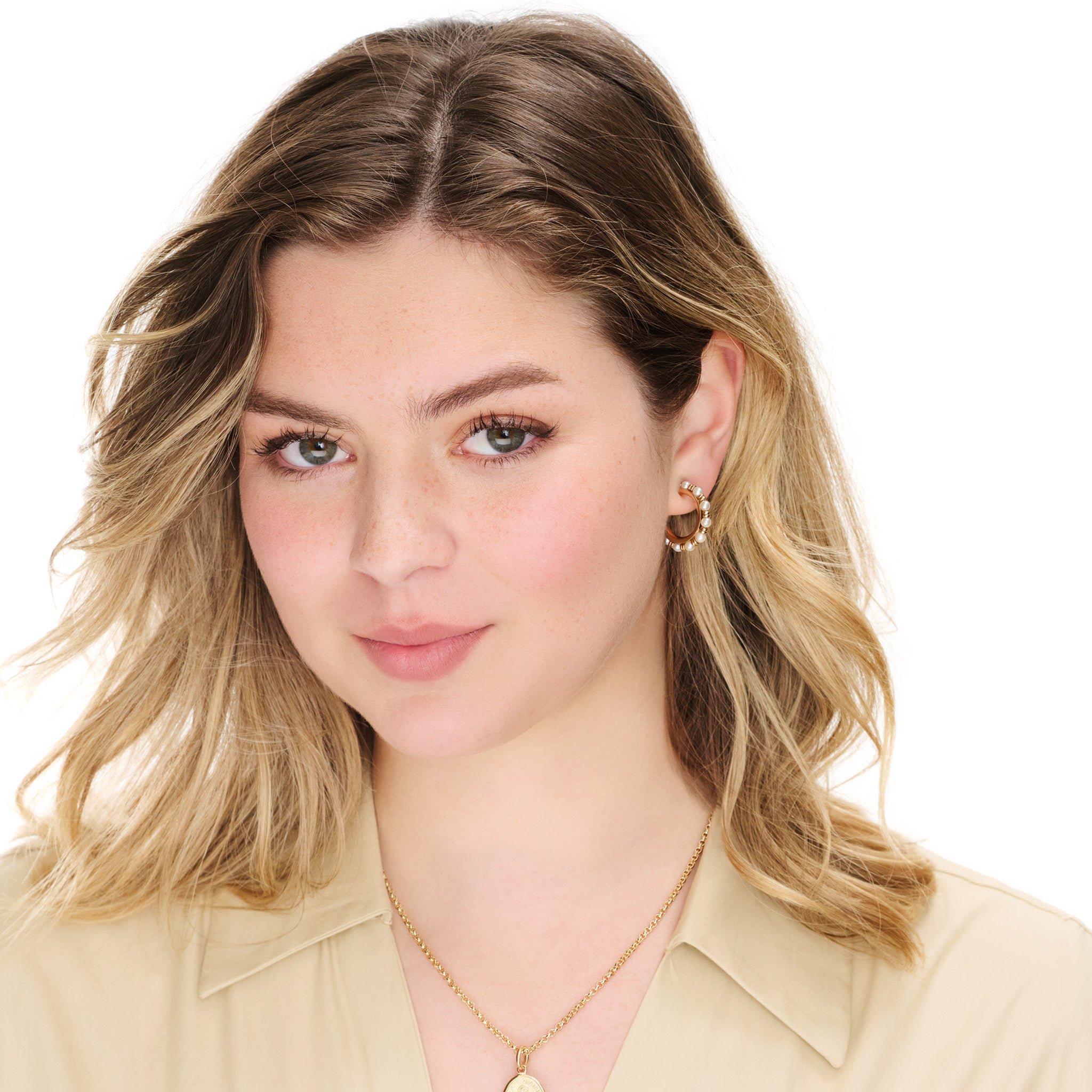 Model wears handcrafted yellow gold hoop earrings featuring small gold beads and pearls.