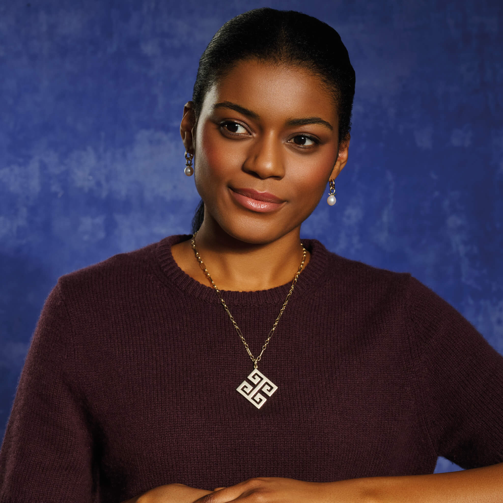 Model wearing handcrafted yellow gold necklace pendant featuring a Greek key pattern.