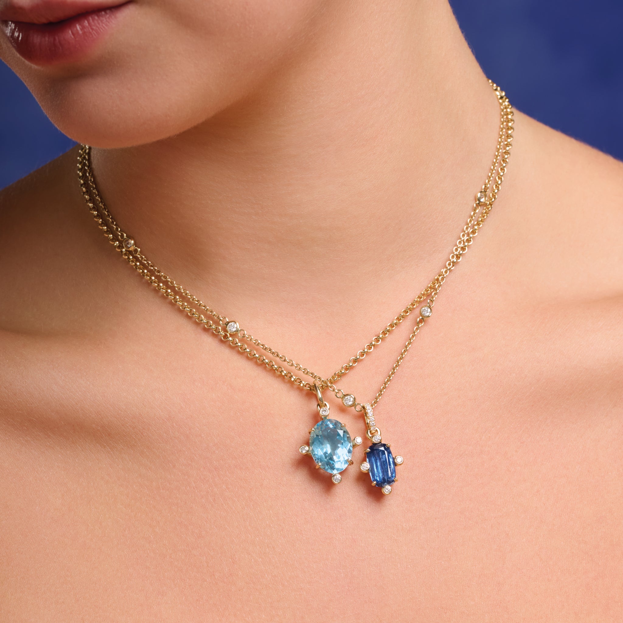 Model wearing handcrafted 9ct yellow gold pendant with medium facetted blue gemstone set with four diamonds, on gold chain.
