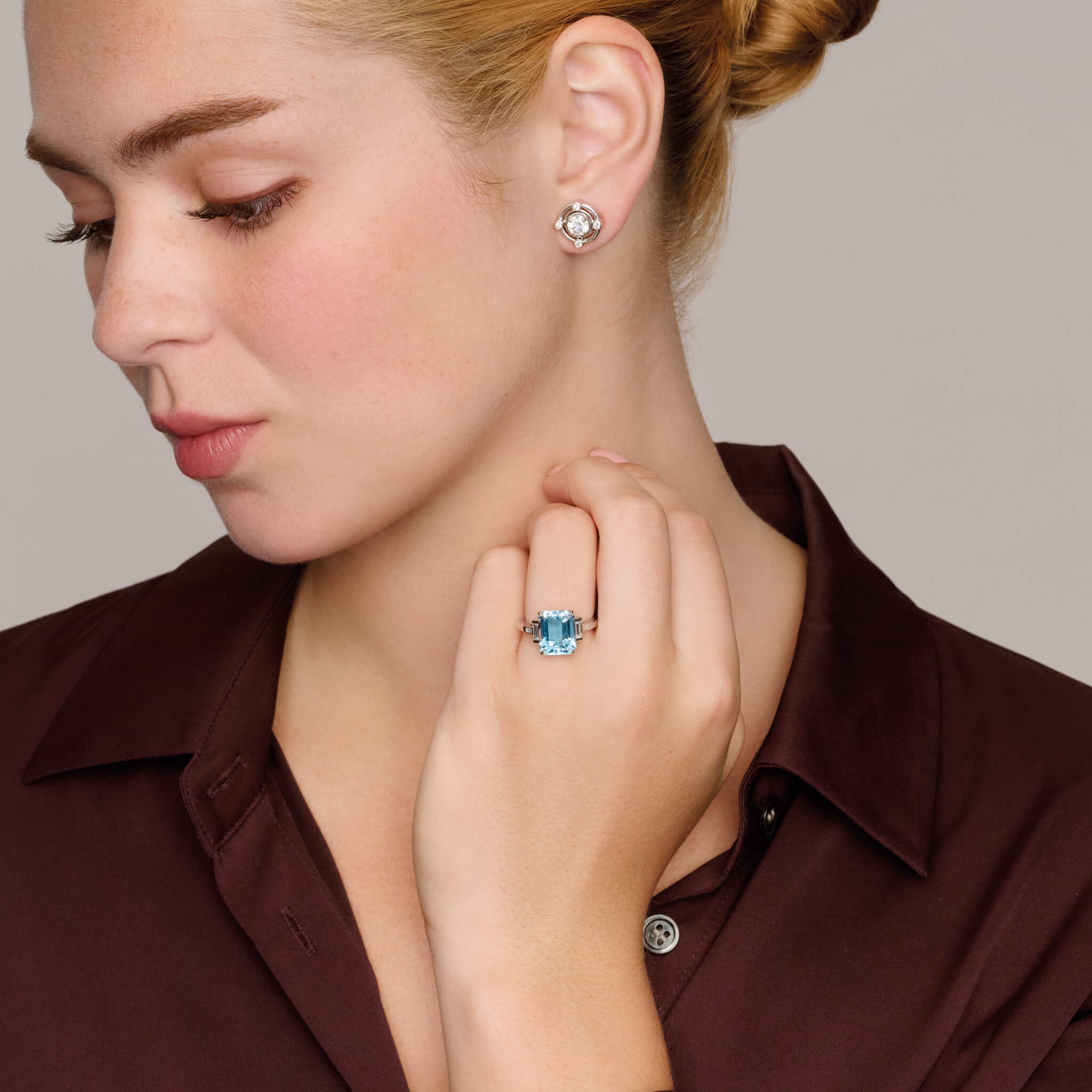Model wearing handcrafted platinum ring featuring a central emerald cut blue aquamarine flanked by two smaller rectangular diamonds on each side and a pair of baguette cut diamonds, all set in a sleek band.