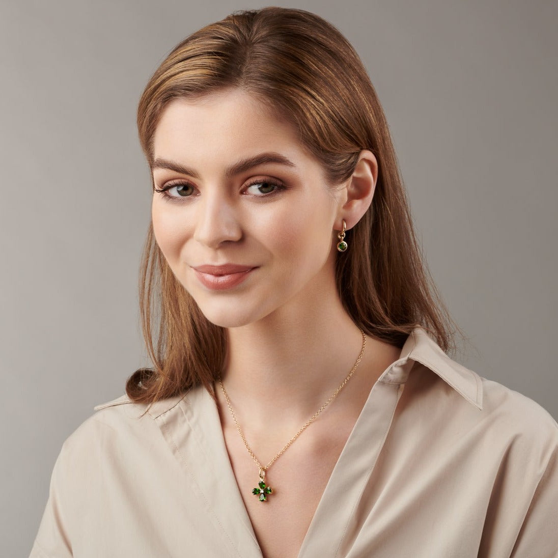 Model wearing a handcrafted yellow gold four-leaf clover necklace pendant with precious stones.