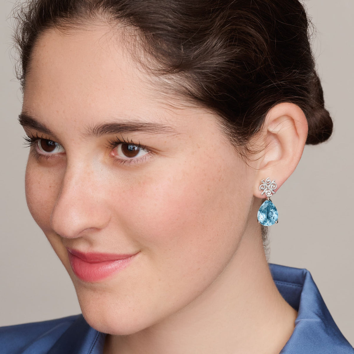 model wears handcrafted 9ct white gold Luiza stud earring pendants with facetted blue topaz, inspired by Rio de Janeiro, November Birthstone