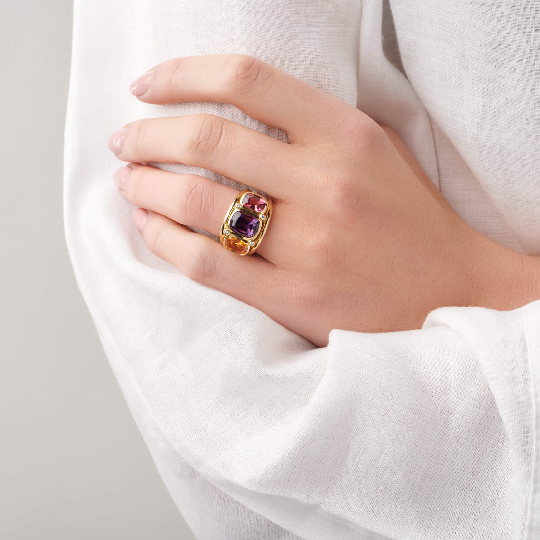 Model wearing a handcrafted 18ct yellow gold ring featuring rectangular shaped precious gemstones