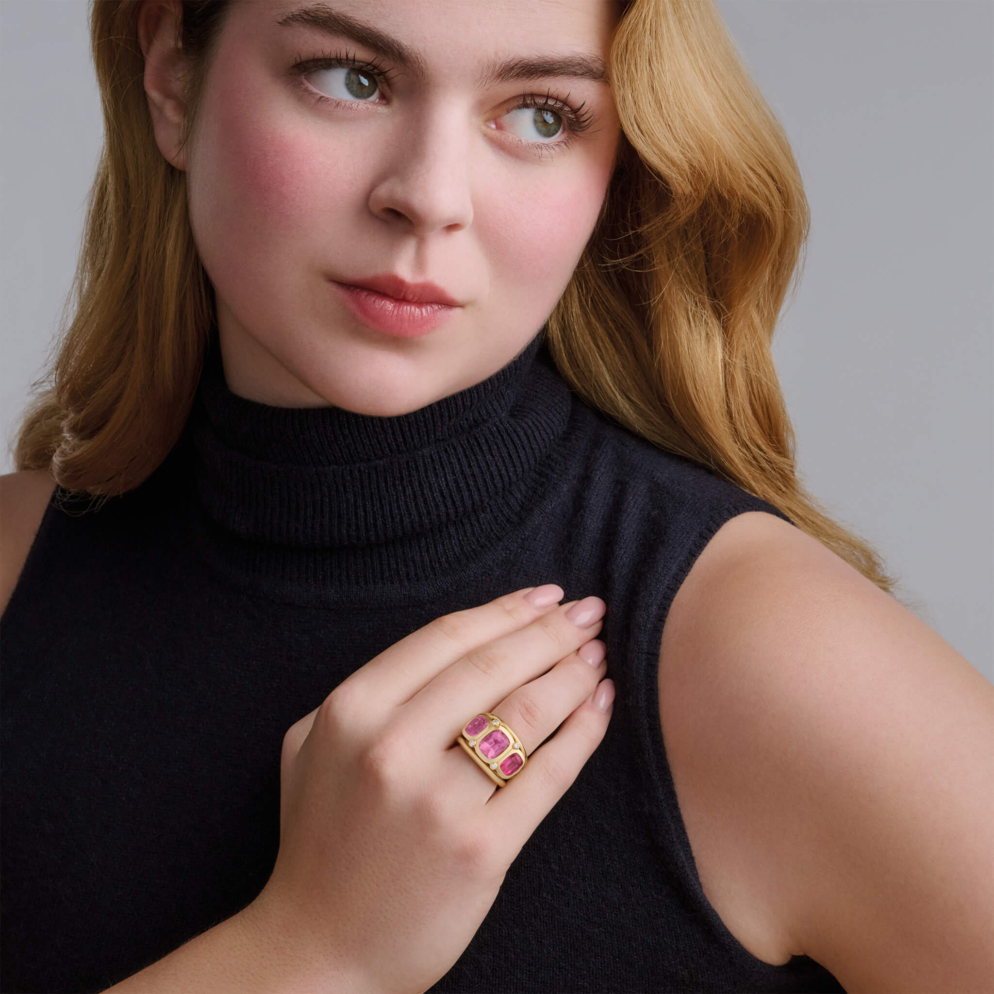 Model wearing a handcrafted 18ct yellow gold ring featuring rectangular shaped precious gemstones.