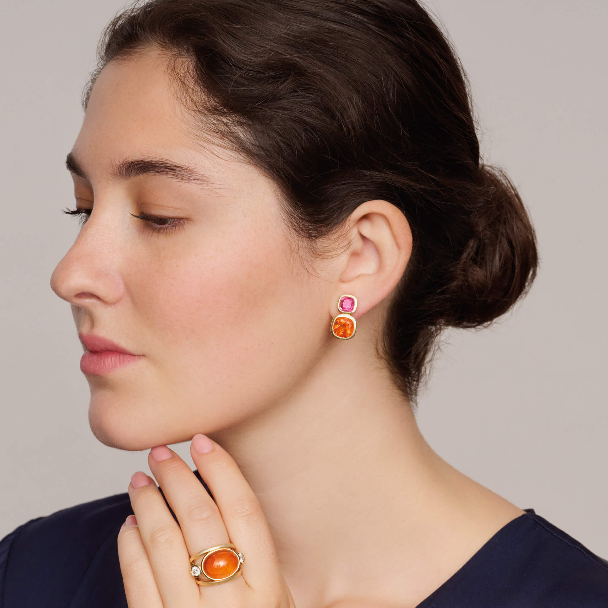 Model wears handcrafted 18ct yellow gold square shaped earrings featuring precious gemstones