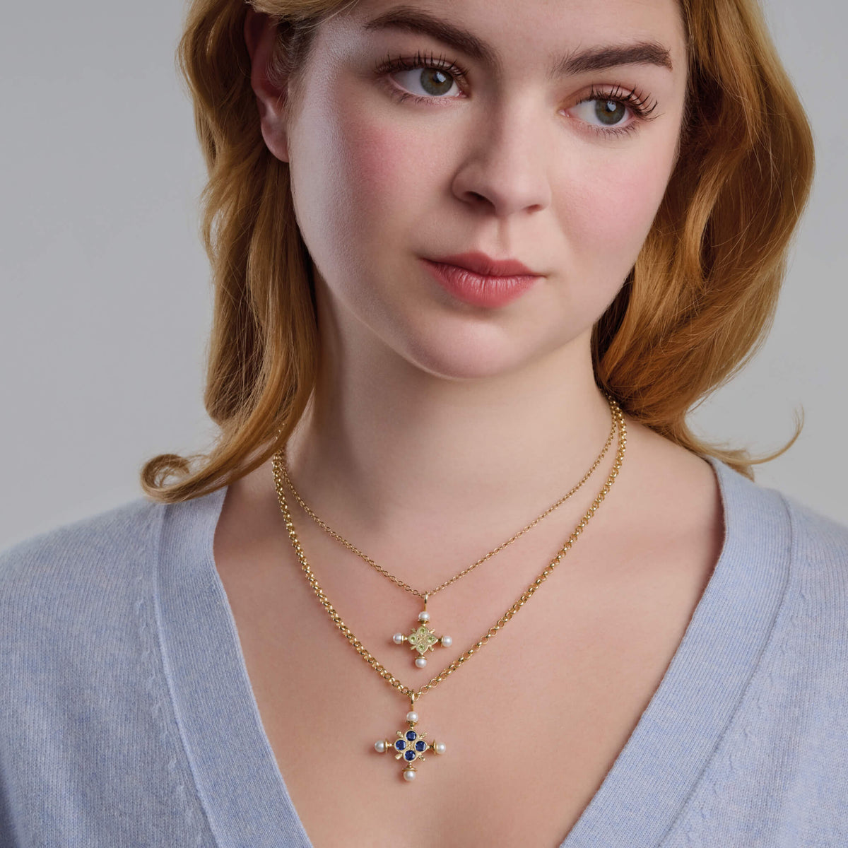 Model wears Madrid Large Cross with four facetted dark blue sapphires and four pearls. The perfect christening gift for those born in September.