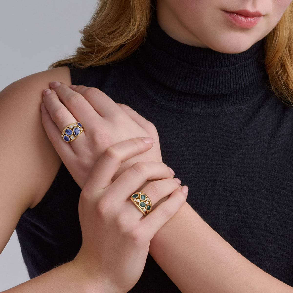 Model wears handcrafted 18ct yellow gold ring featuring four soft blue ceylon sapphires and smaller diamonds, September birthstones.
