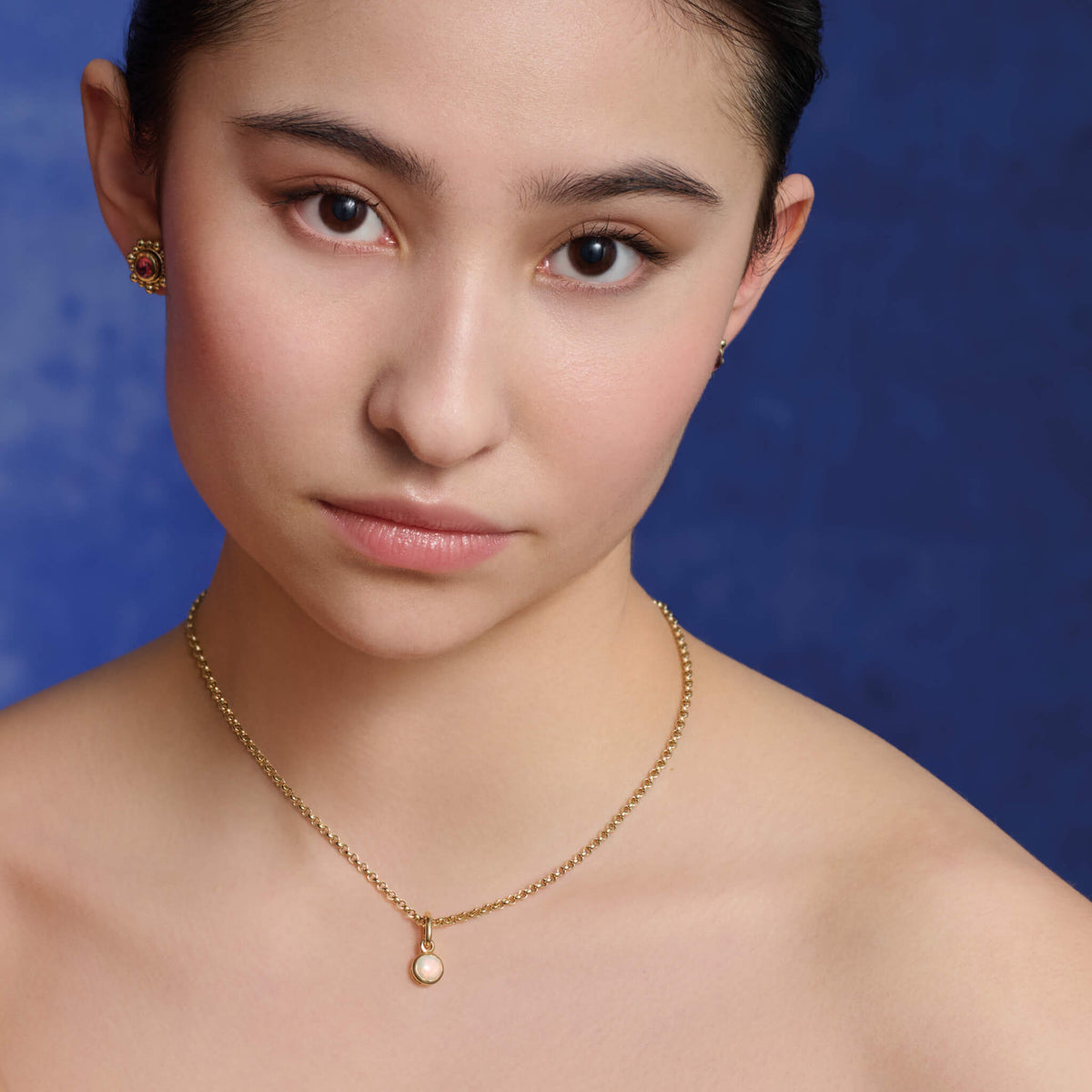 Model wears a handcrafted Talya necklace pendant in yellow gold featuring a round moonstone drop.
