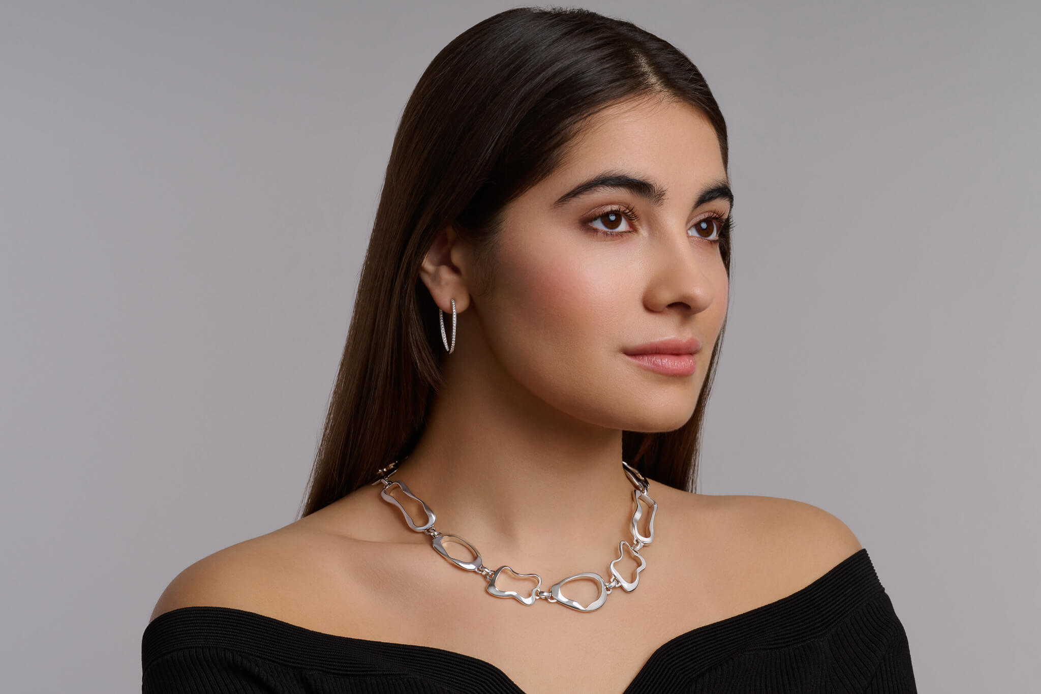 model wears silver necklace inspired by French pastries and white gold and diamond earrings.