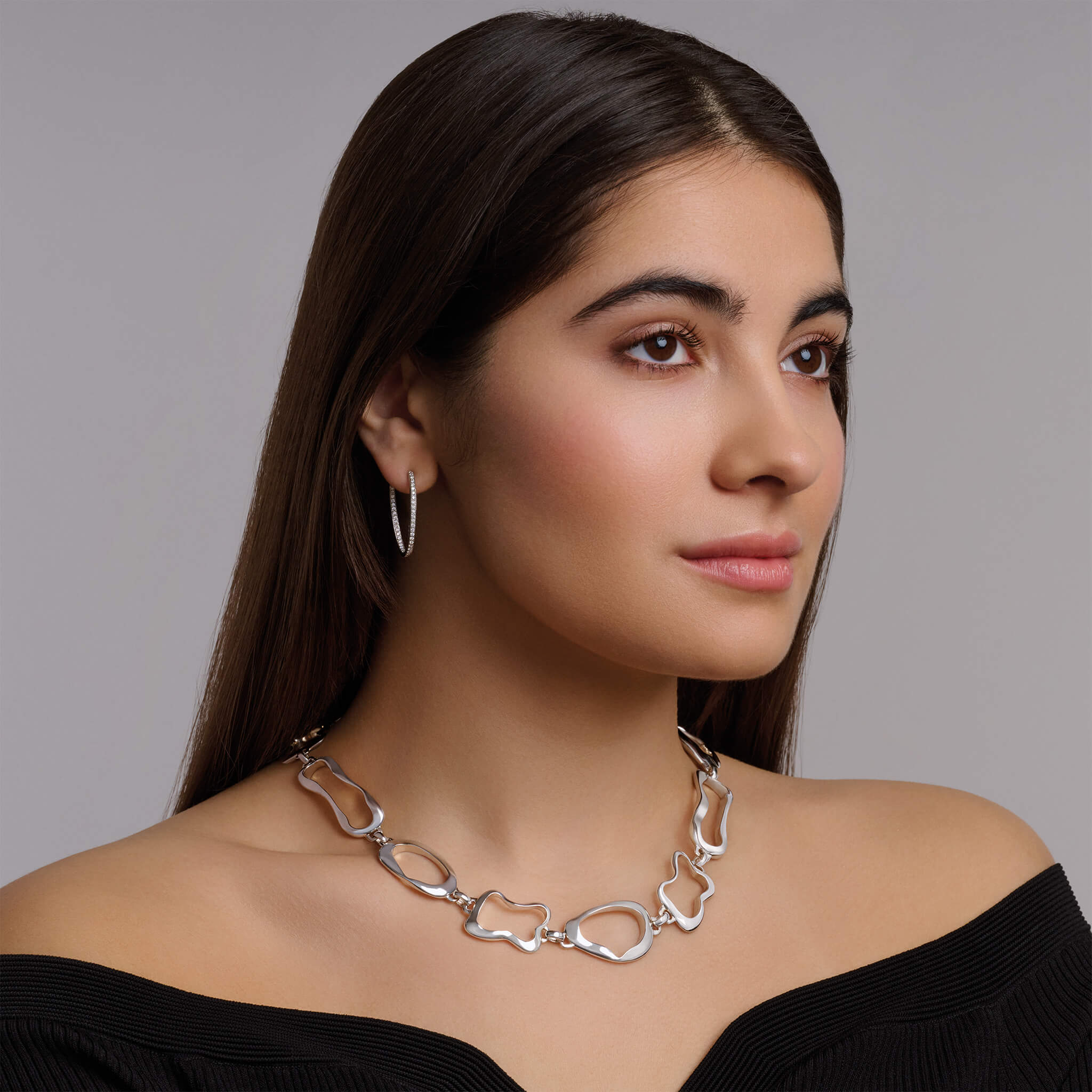 Model wearing a handcrafted sterling silver necklace featuring the outlines of french pastries: eclair, canele, pain au chocolat and croissant.