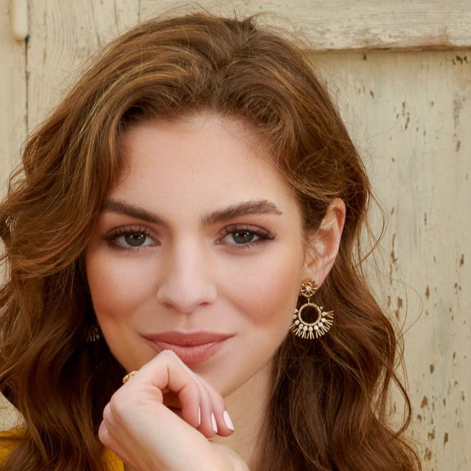Model wearing handcrafted yellow gold earrings in the shape of dried palm fronds from Morocco.