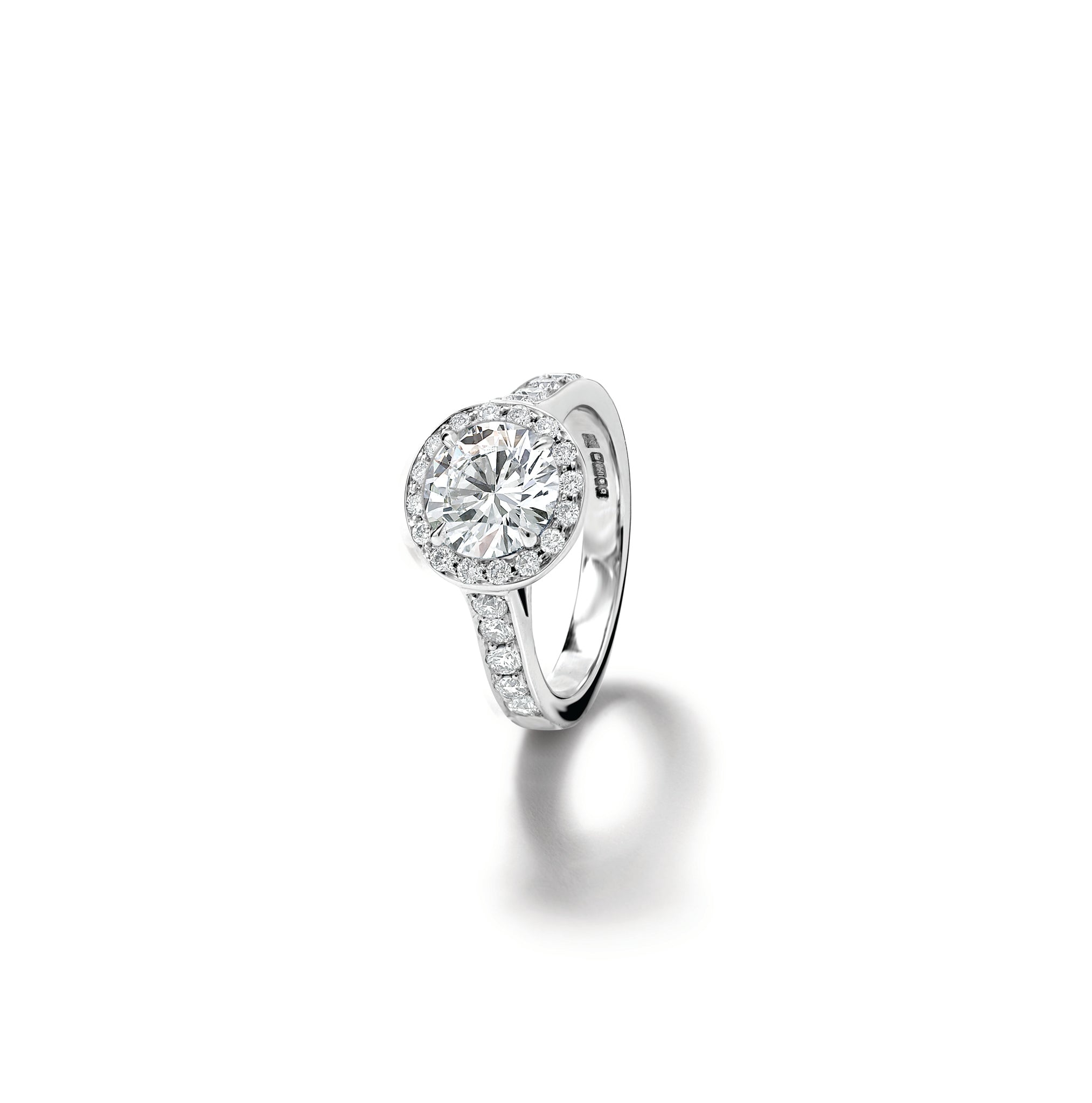 Model wears handcrafted platinum engagement ring with a round diamond at the centre, surrounded by diamond pave.
