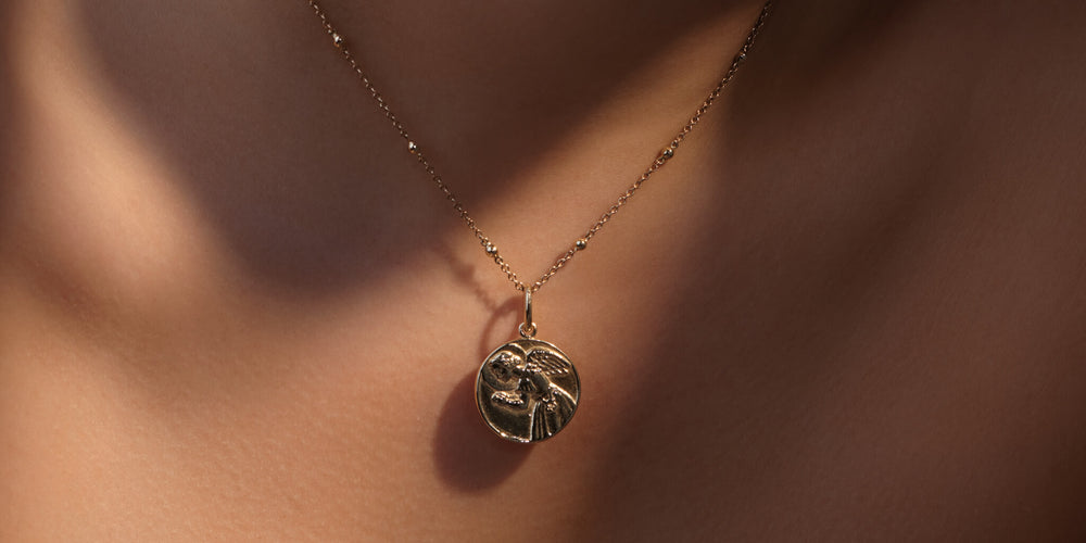 Model wears silver saint pendant on chain