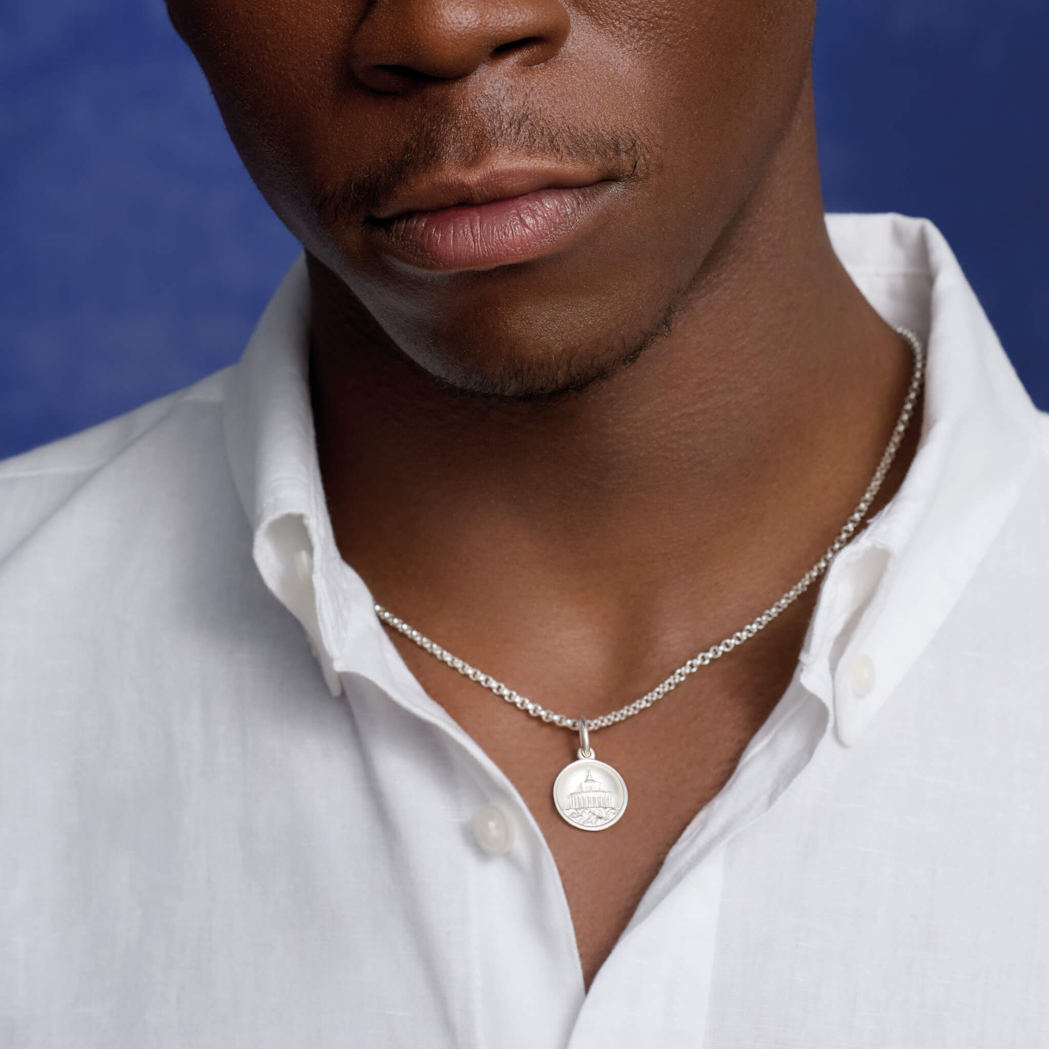 Model wears a handcrafted silver necklace pendant with a lighthouse 'en relief'.