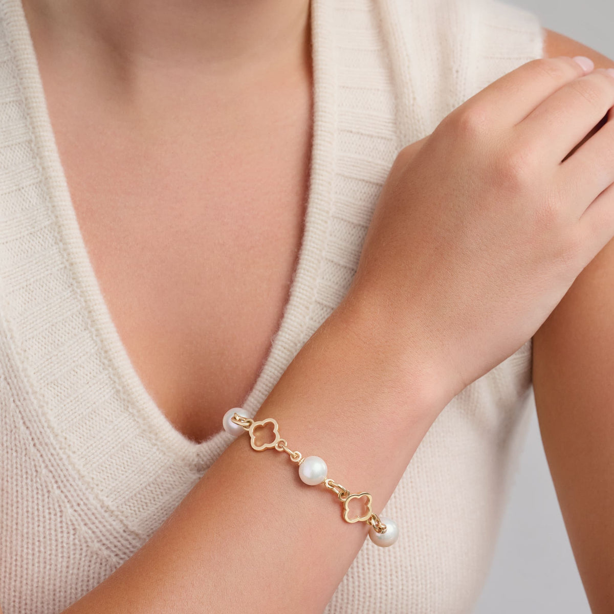 Model wearing a handcrafted yellow gold bracelet with star-shaped links, spaced with pearls, birthstone of June.