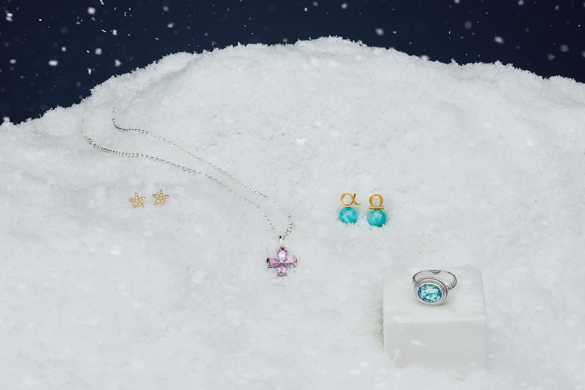 Jewellery for stocking fillers including earrings, necklace, and ring on a snowy background