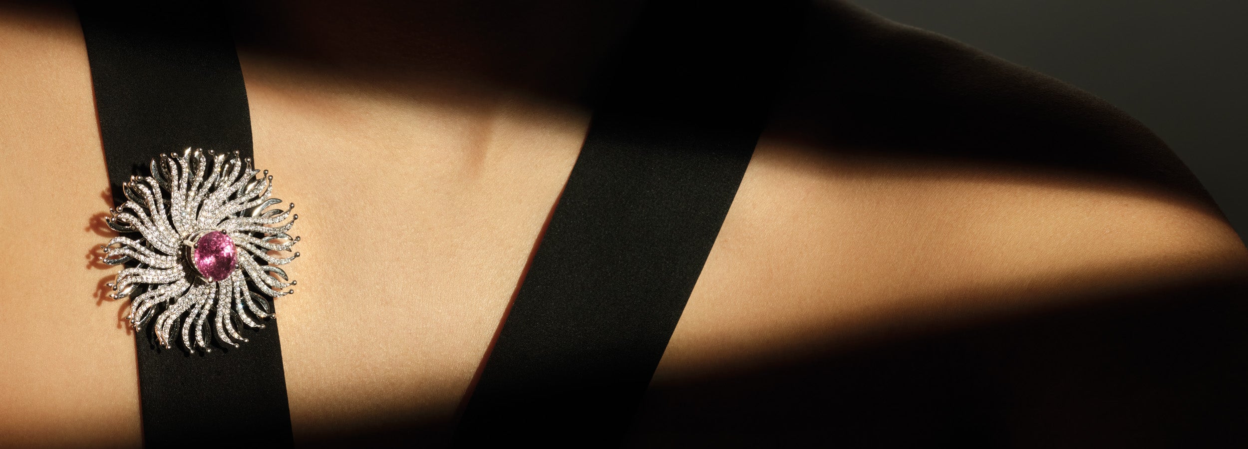 Model wearing the Taj Mahal necklace pendant featuring a spiderweb-like design with a central pink sapphire gemstone.