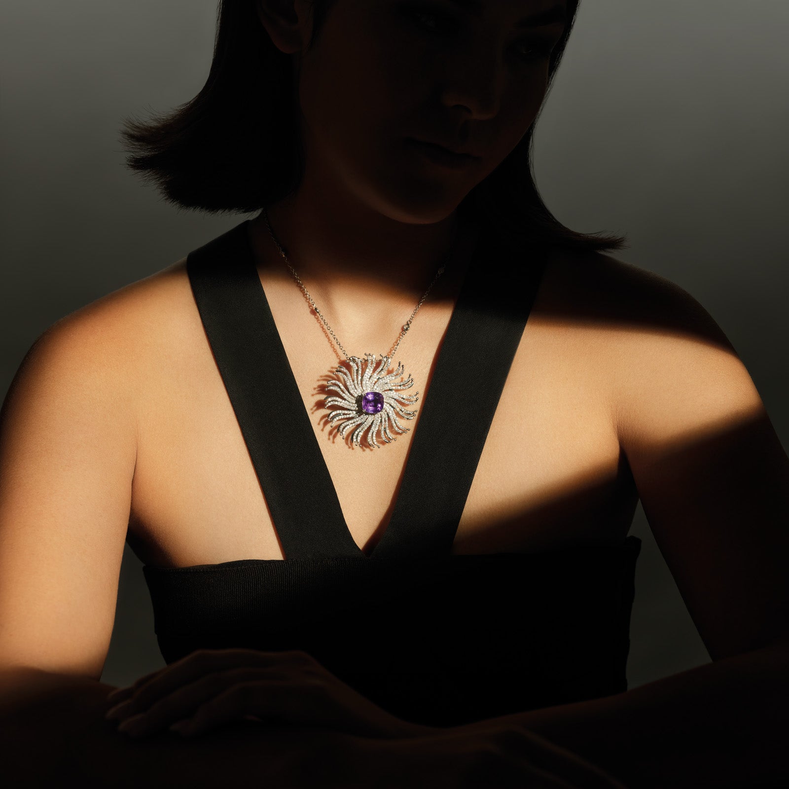 Model wearing the Taj Mahal necklace pendant featuring a spiderweb-like design with a central amethyst gemstone.