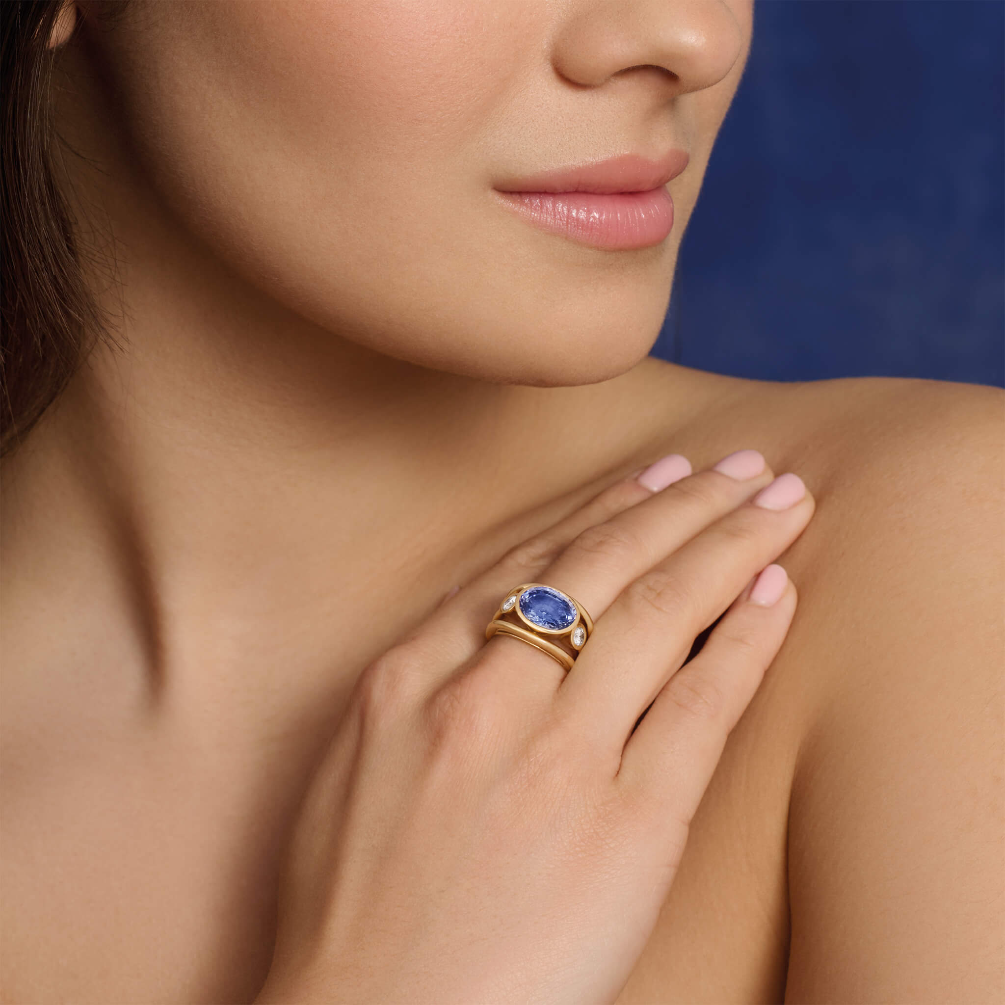 Model wearing sapphire Aeneus ring with diamonds set in yellow gold.
