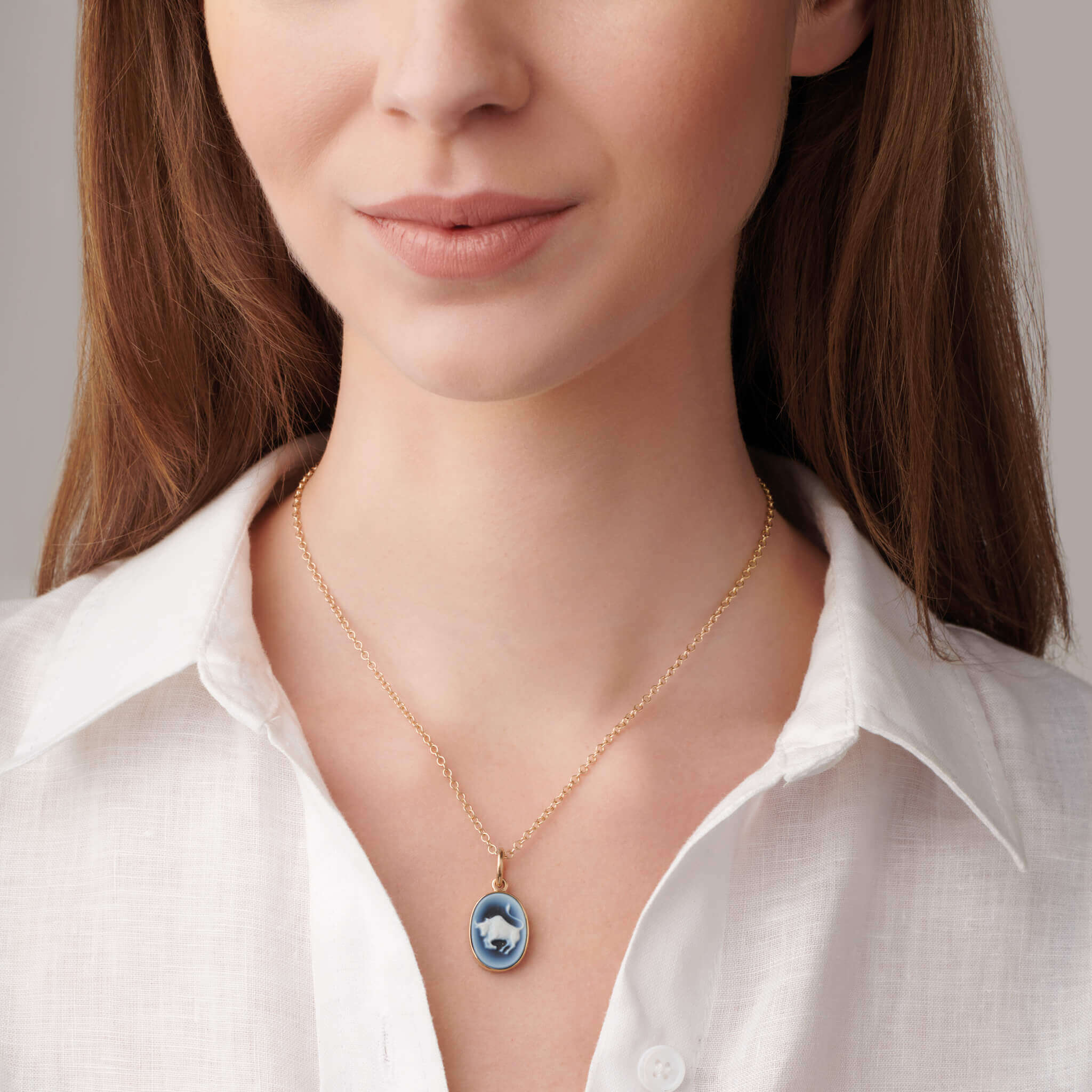 model wears zodiac taurus cameo necklace pendant in yellow gold with blue and white agate, featuring detailed bull motif, inspired by traditional cameo jewellery and handcrafted artisan design, mexico inspired