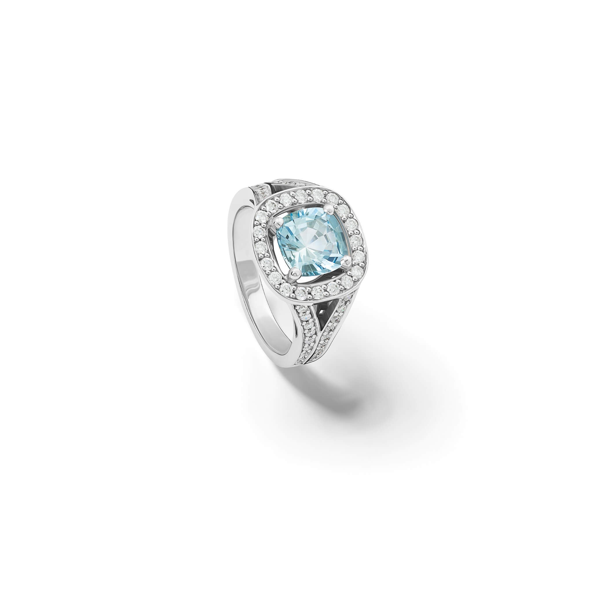 Handcrafted 18ct white gold engagement ring featuring a claw set cushion-cut aquamarine surrounded by a halo of small diamonds and smaller diamonds embedded along the band.