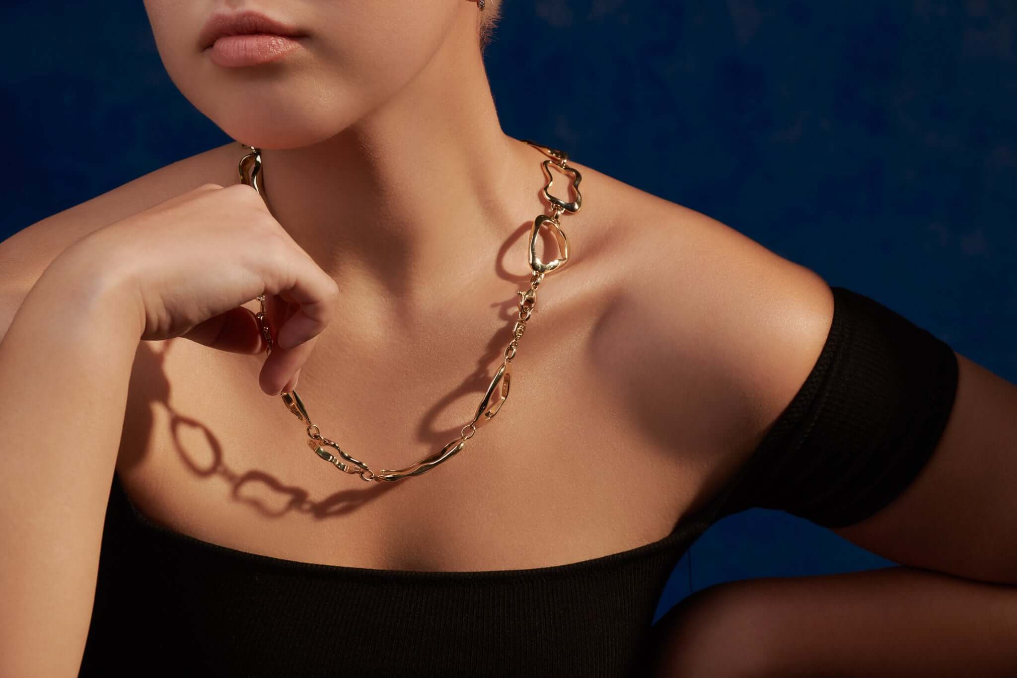 Model wearing handcrafted yellow gold necklace featuring different shapes of pastries, inspired by French cafés.