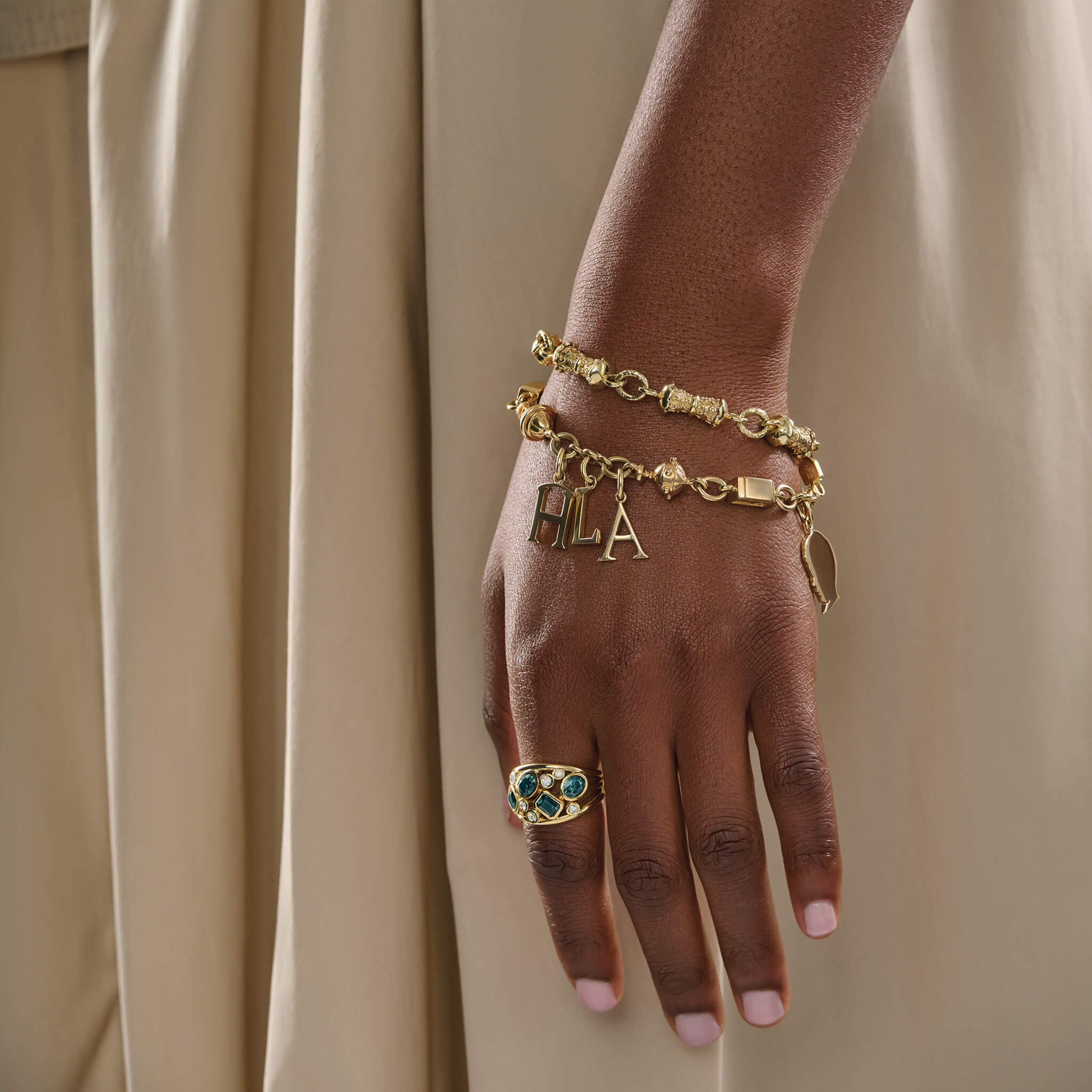 Model wearing handcrafted yellow gold customisable bracelet with charms.