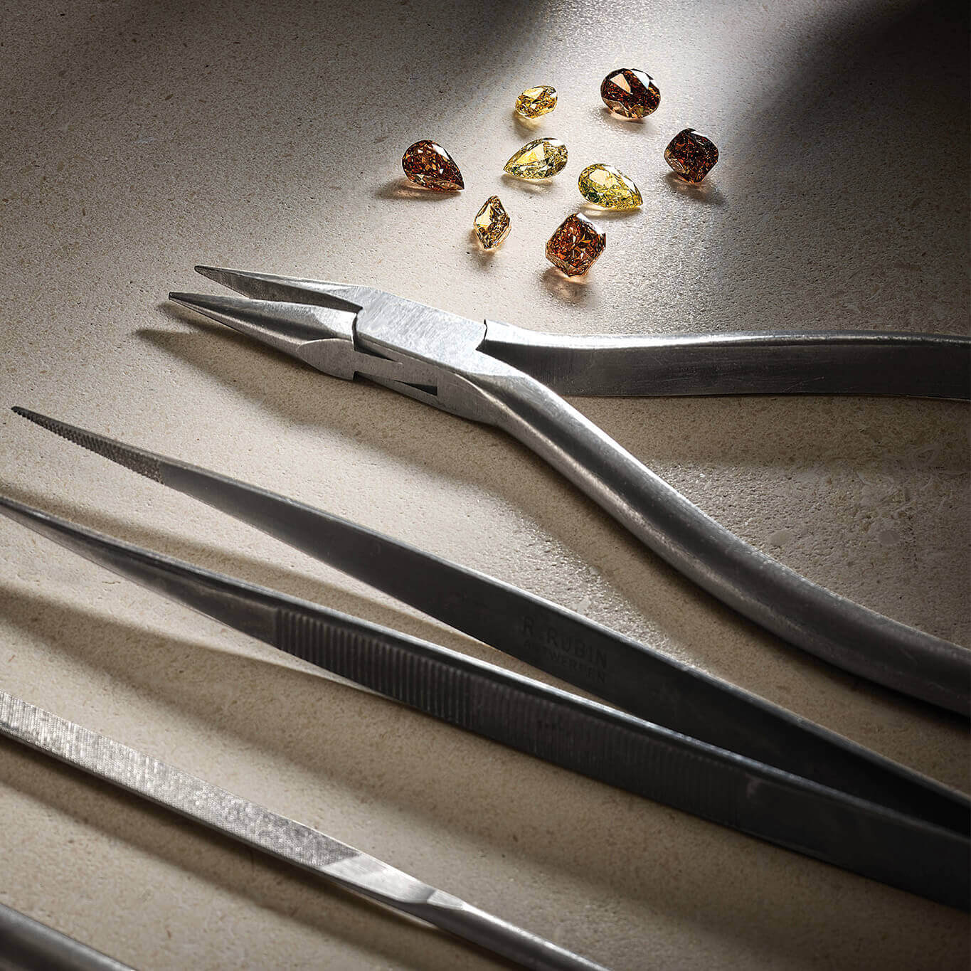 Jewellery tools next to brown and yellow precious stones.