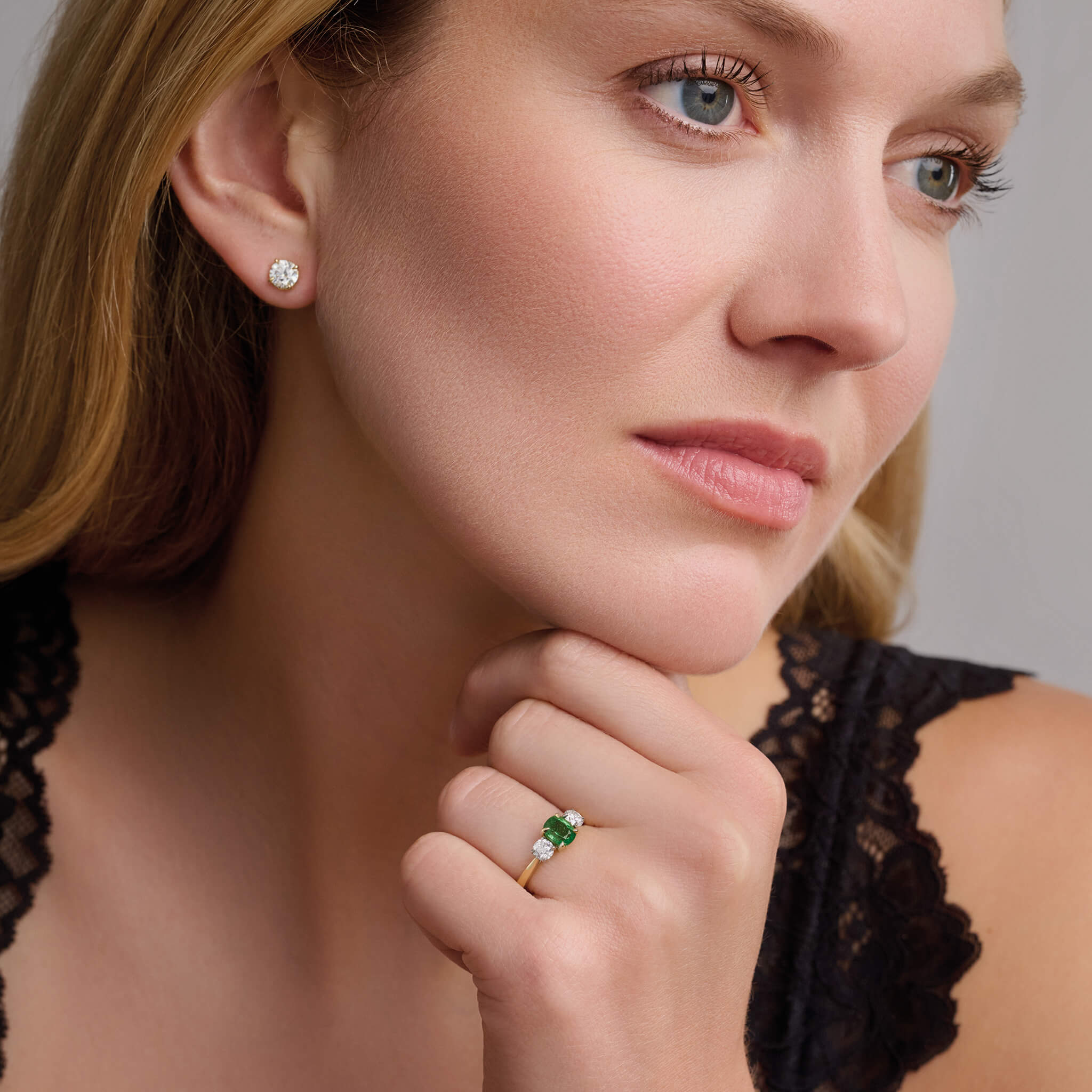Model wears Handmade 18ct yellow gold engagement ring featuring a large, cushion cut tsavorite garnet at its center, surrounded by two smaller teardrop-shaped white diamonds.