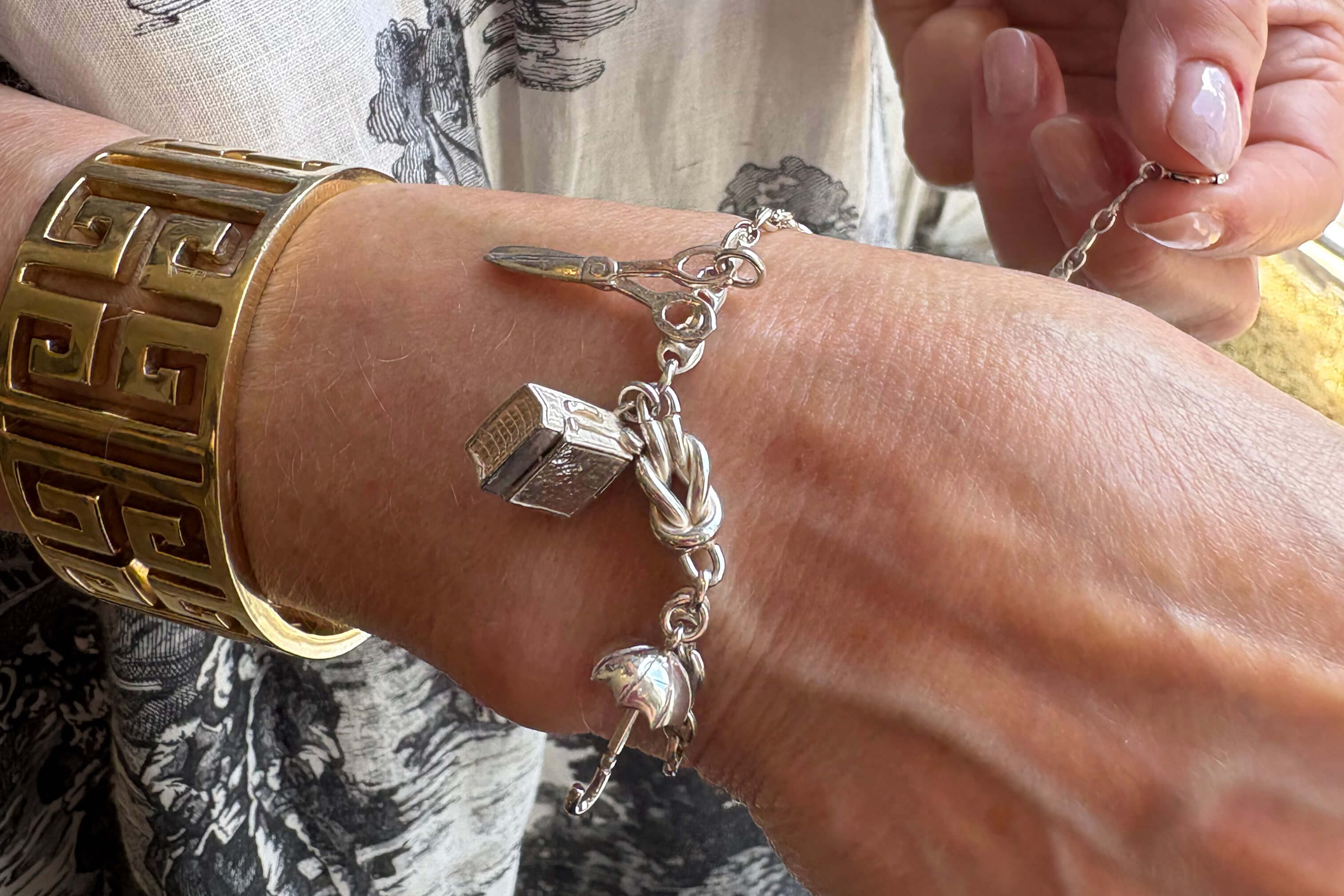 Cassandra holds a vintage silver charm bracelet with charms.