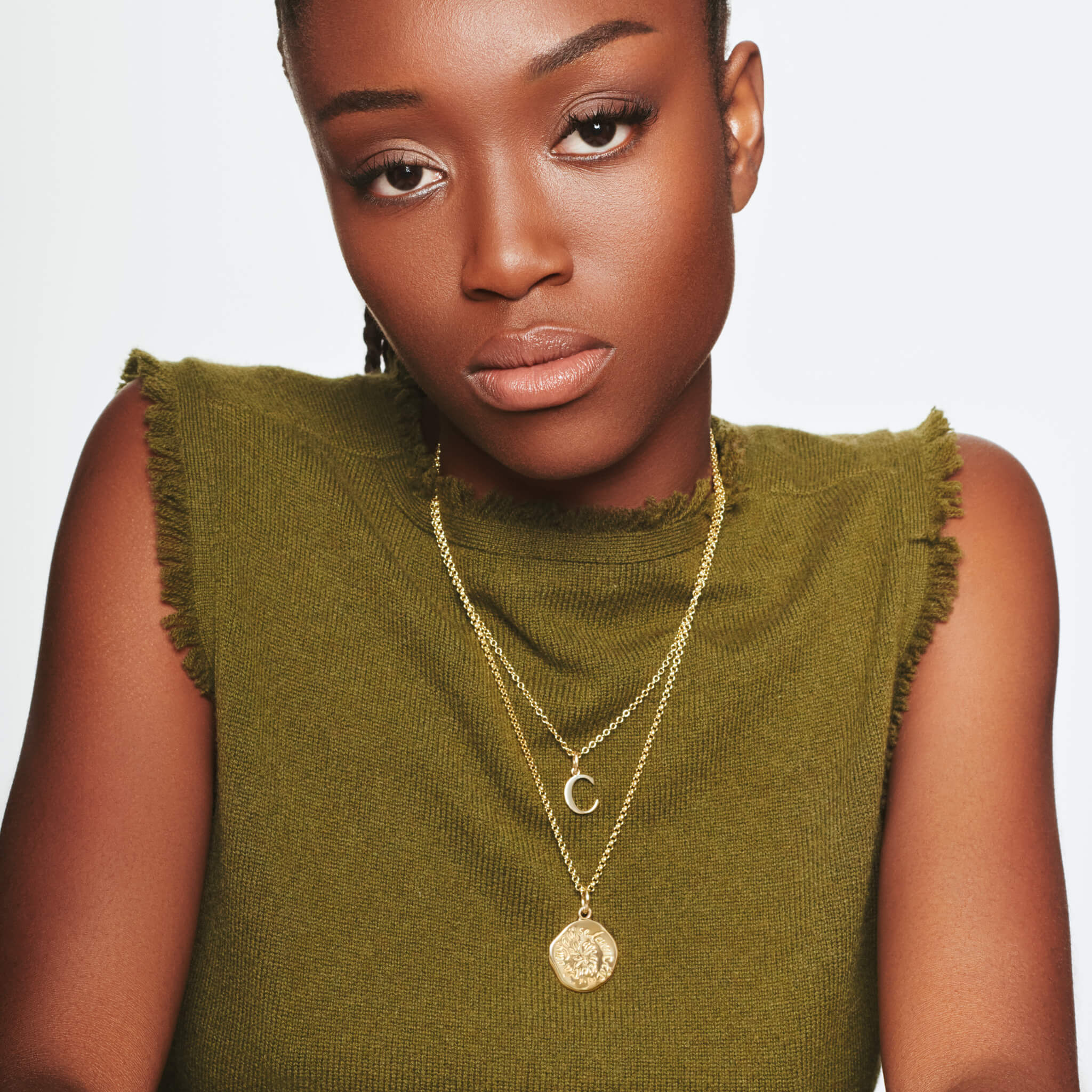 Model wearing a handcrafted round yellow gold pendant necklace engraved with a quote on aspiration.