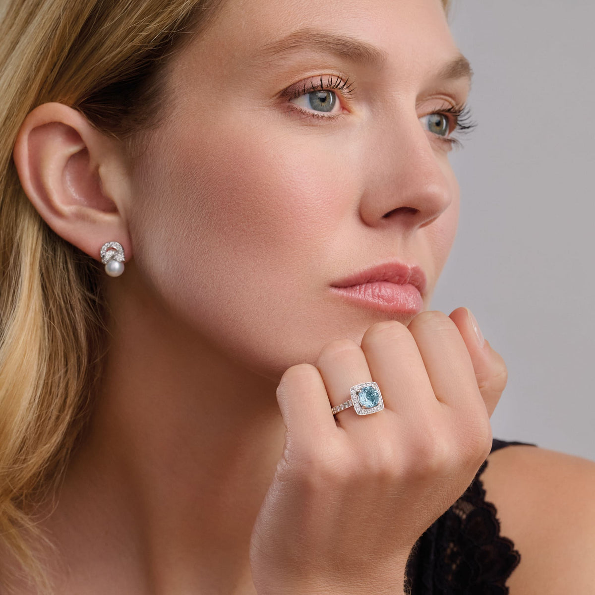 Model wears Handcrafted engagement ring in 18ct white gold with a central round cut aquamarine surrounded by a square halo of pav� diamonds with a pav� diamond shank.