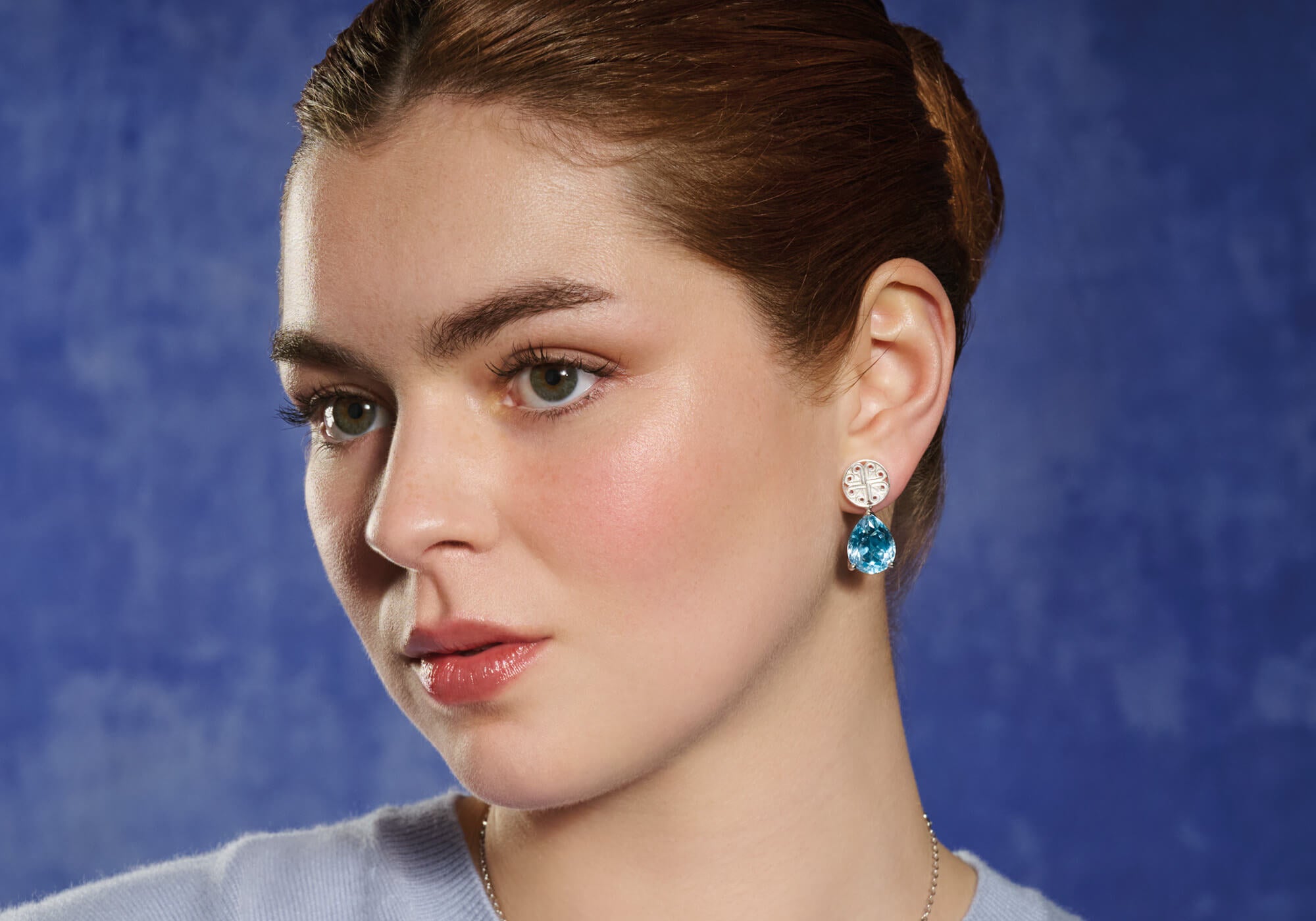 Model wears handcrafted interchangeable silver circular stud earrings with a cross-like motif in the centre.