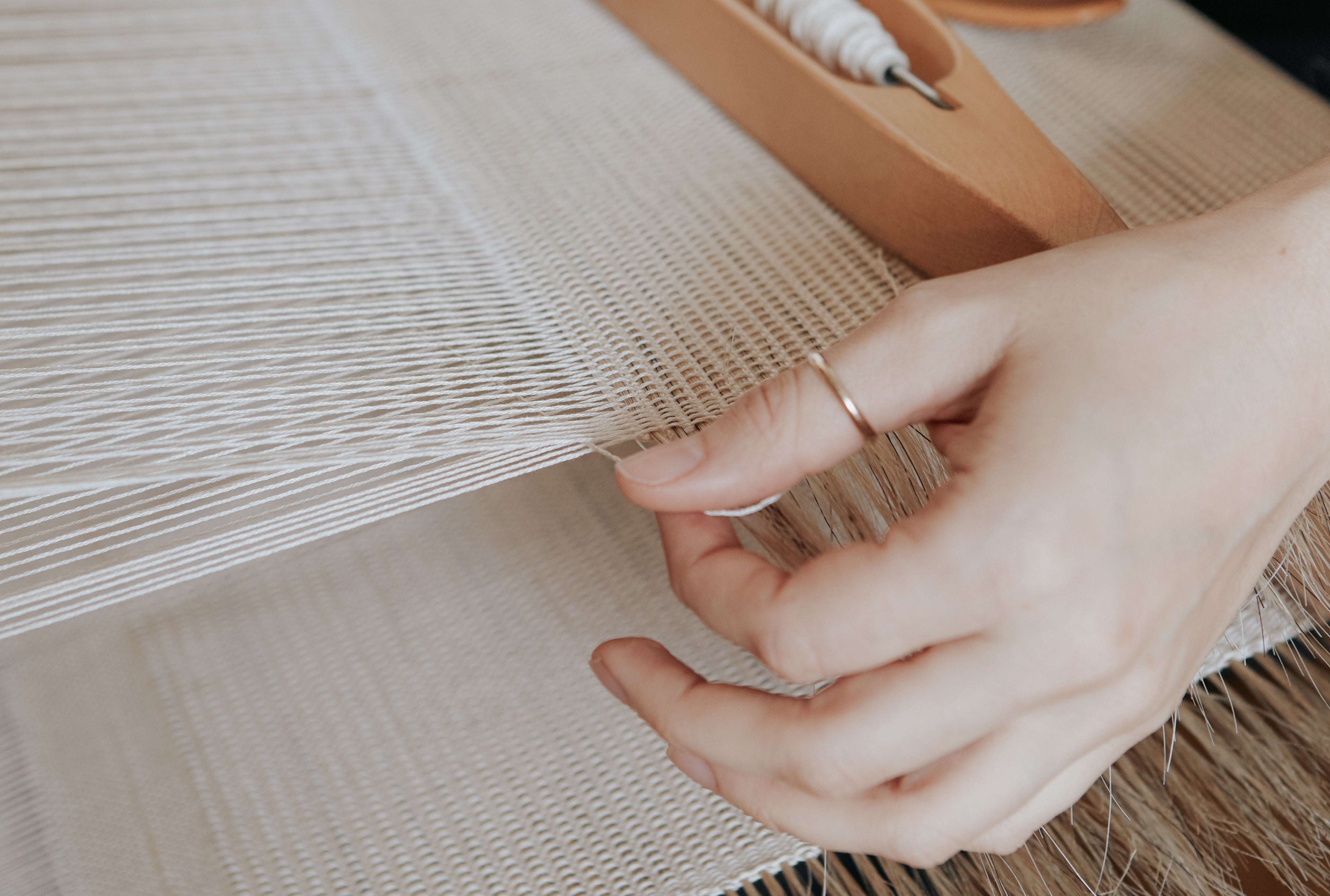 Close up image of Maria Sigma's hands weaving a textile.
