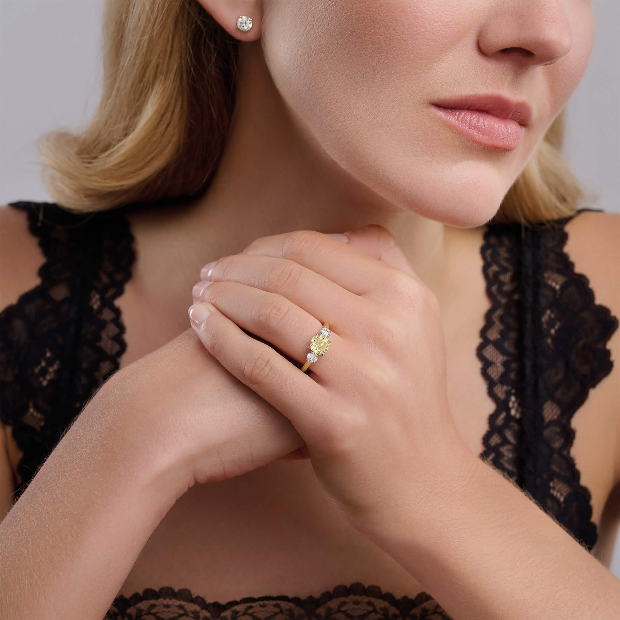 Model wears handcrafted yellow gold yellow diamond engagement ring with two diamonds set in white gold on each side