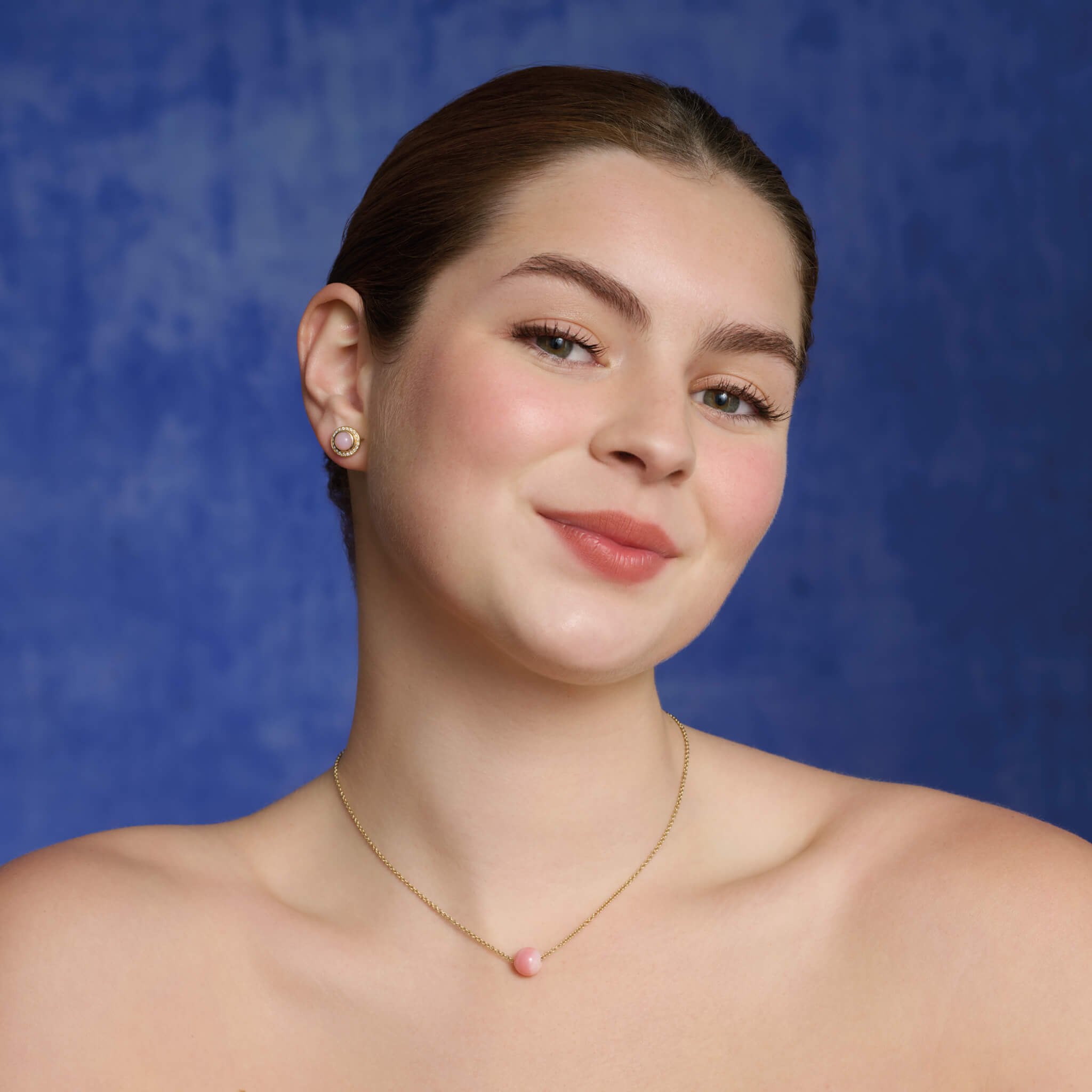 Model wears the handcrafted Pelota necklace in yellow gold with Peruvian pink opal, birthstone of October