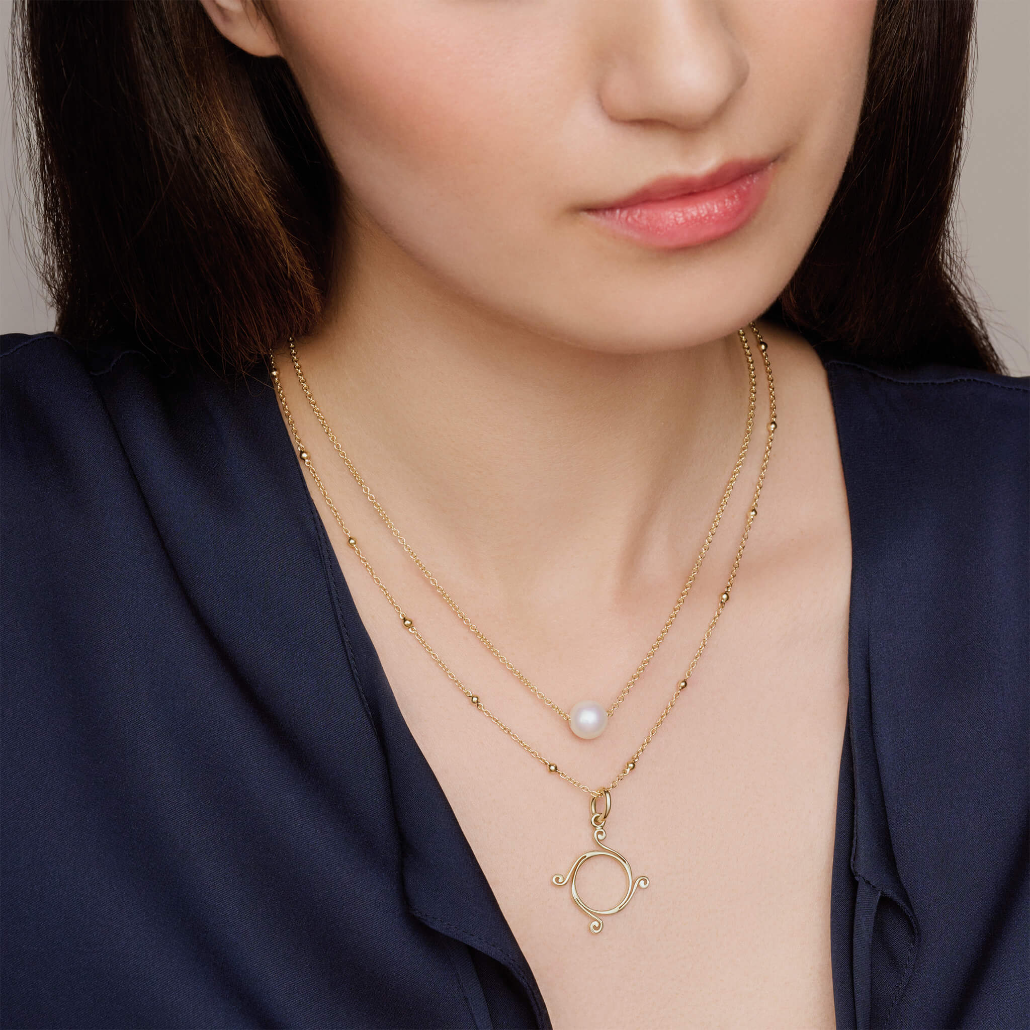 Model wears handcrafted yellow gold necklace featuring a round pearl, birthstone of June.