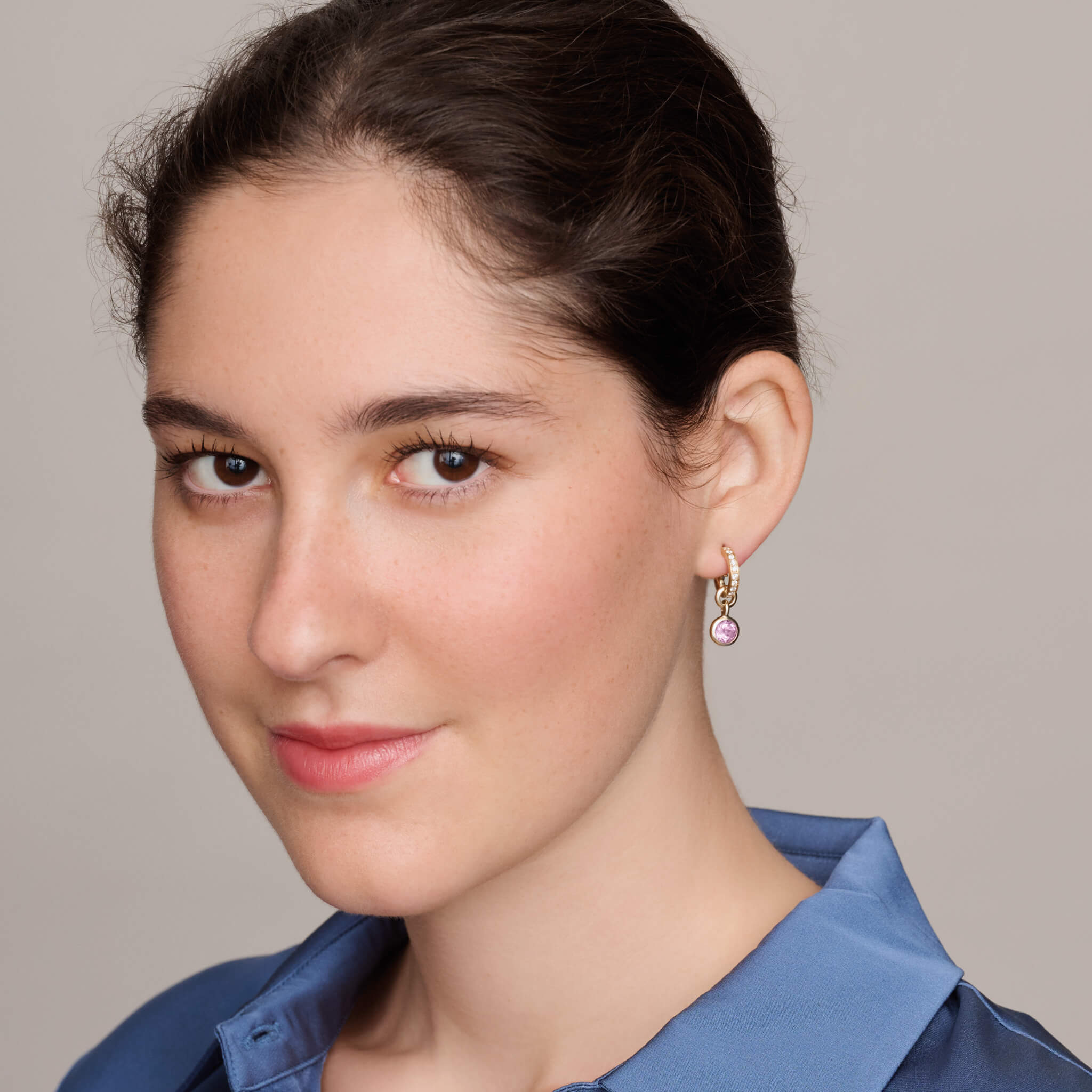 Model wears handcrafted yellow gold earring drops with round pink amethyst, birthstone of February.