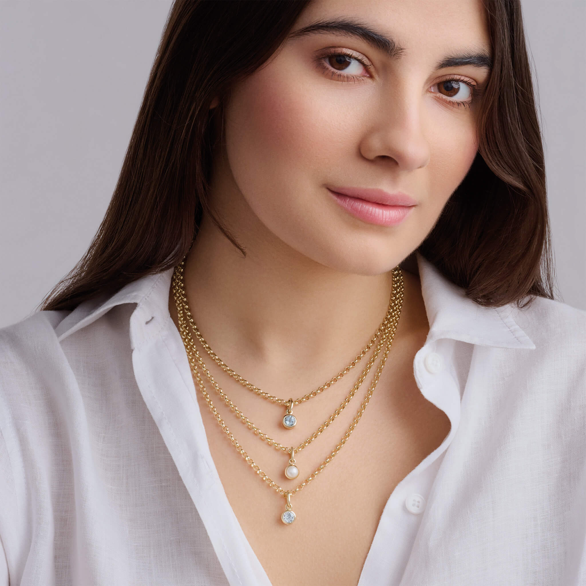 Model wears handcrafted necklace pendant in yellow gold featuring a round precious gemstone drop, birthstones