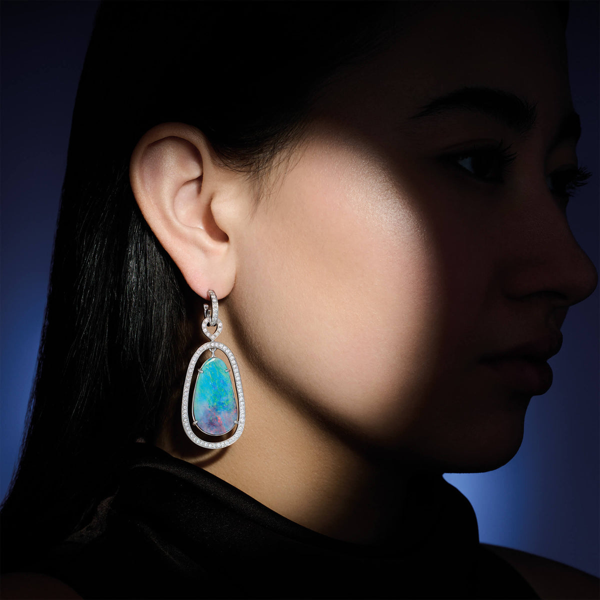 Model wearing handcrafted high jewellery Octavia Margarita occasion earrings in white gold with diamond and opal centre
