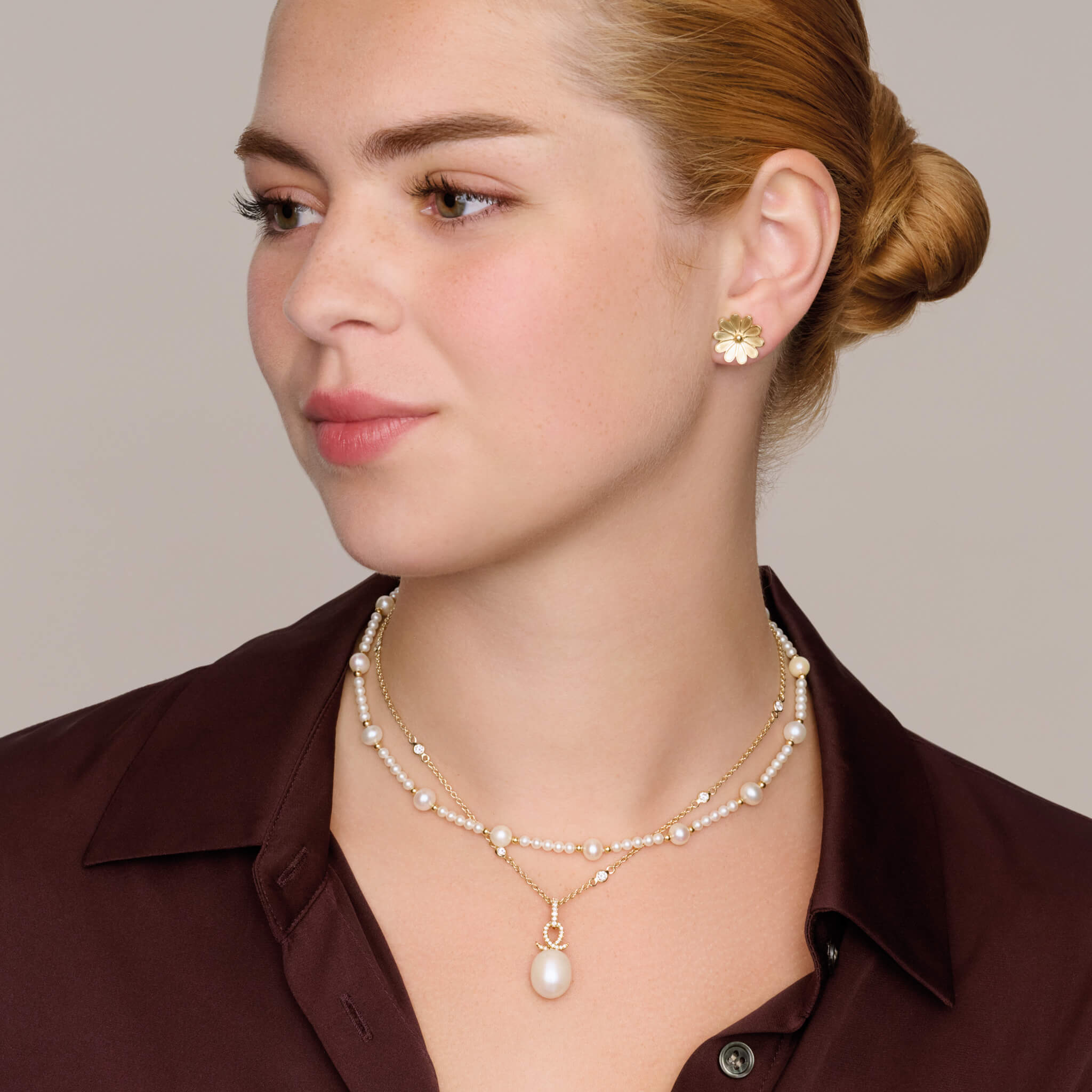 model wearing handcrafted 18ct precious metal necklace pendant with an oval pearl and a diamond oval loop shape crossing over.