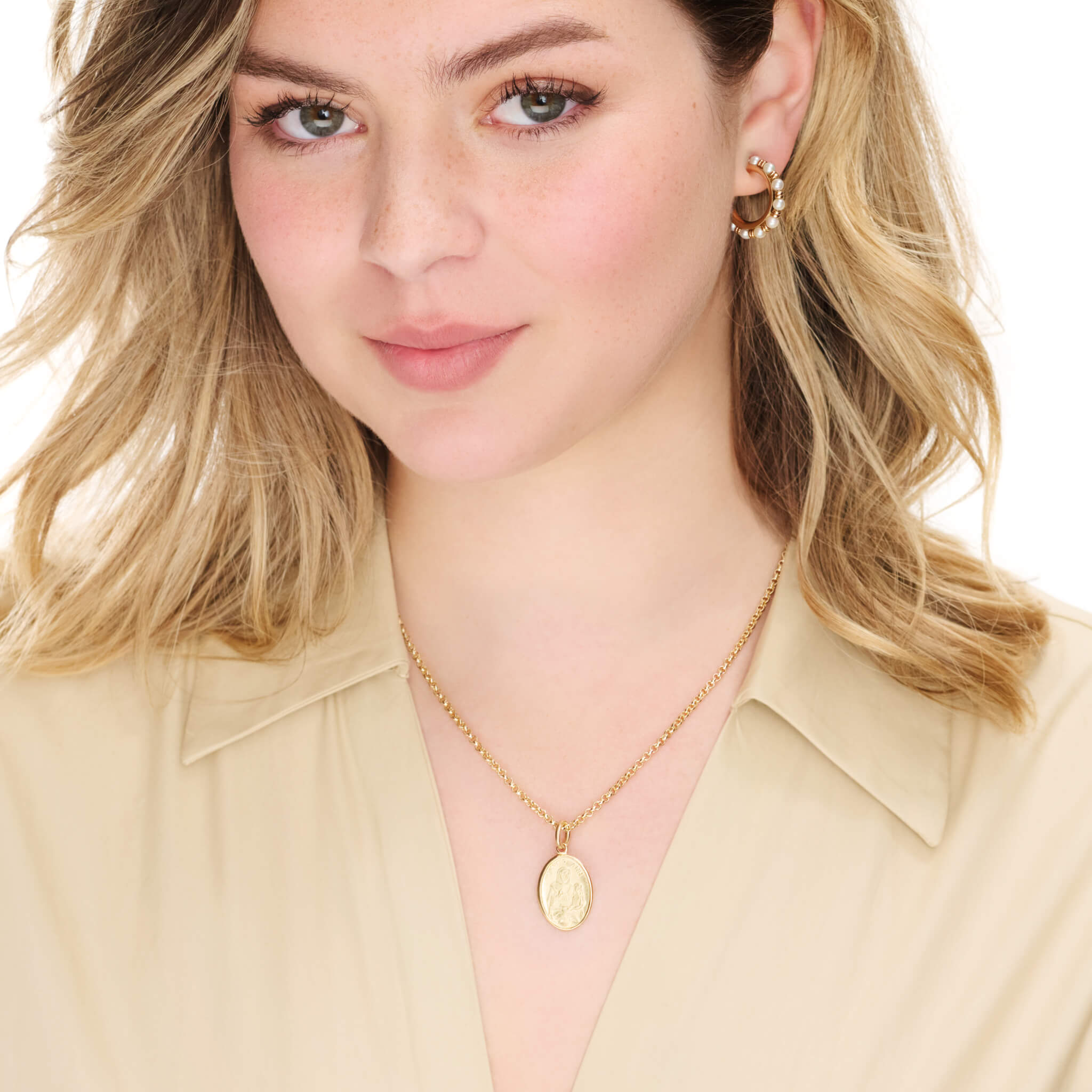 Model wearing handcrafted oval precious metal pendant with an engraving of Saint Anne cradling a child and 'Saint Anne' inscribed above. Includes a top loop for chain attachment.