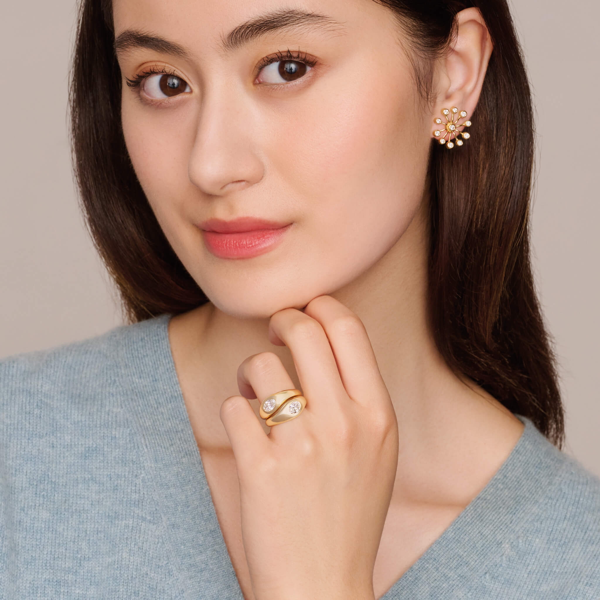 Model wears handcrafted yellow gold ring with a slight teardrop design set with an oval facetted diamond.